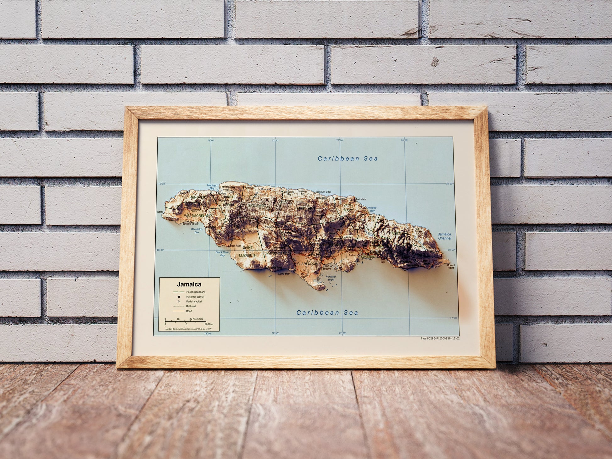 Vintage Jamaica shaded relief map in a wooden frame. Realistic terrain art print for home decor, displayed against a brick wall