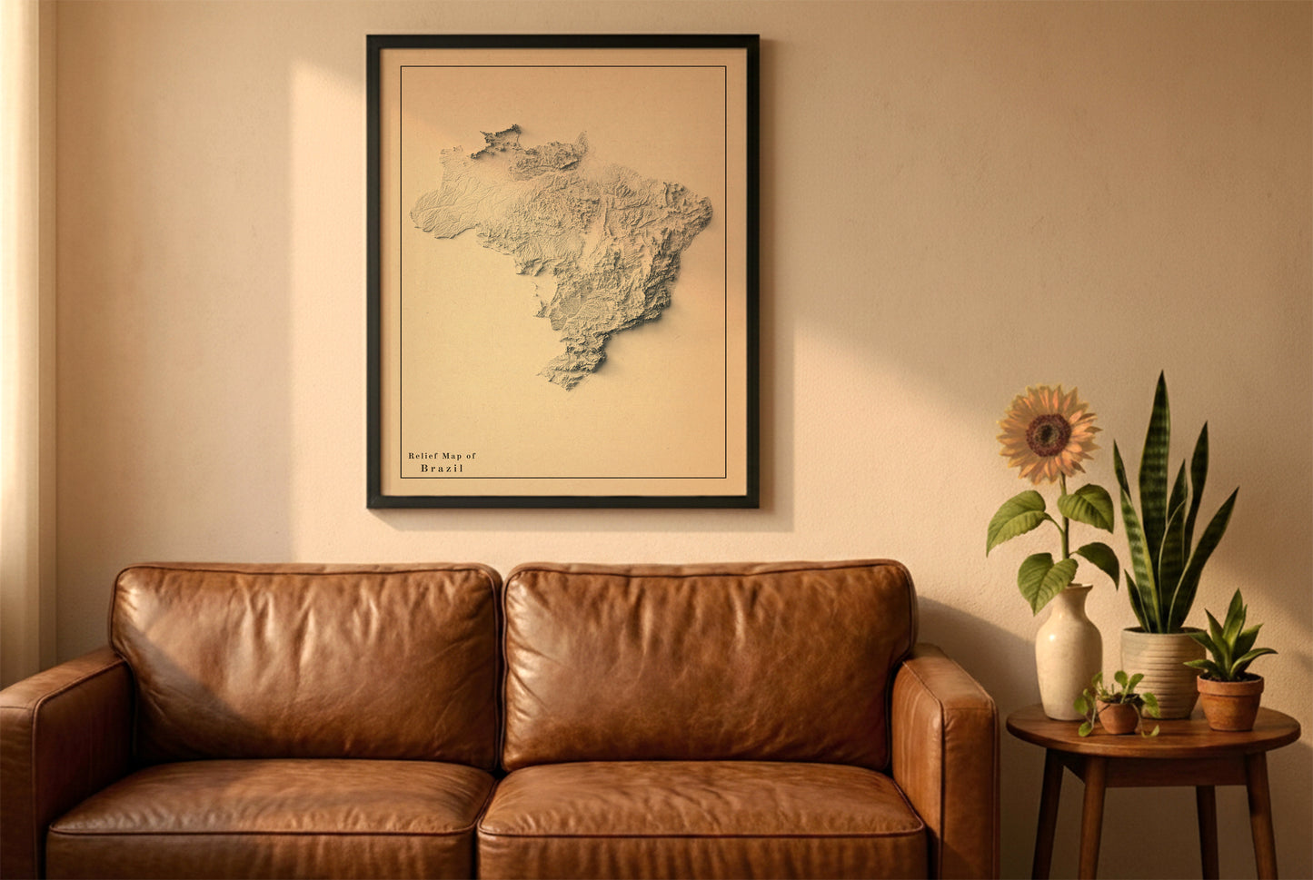 Brazil vintage relief map in a black frame above a brown leather sofa. Boho living room with warm sunlight, sunflower, and indoor plants on a wooden side table