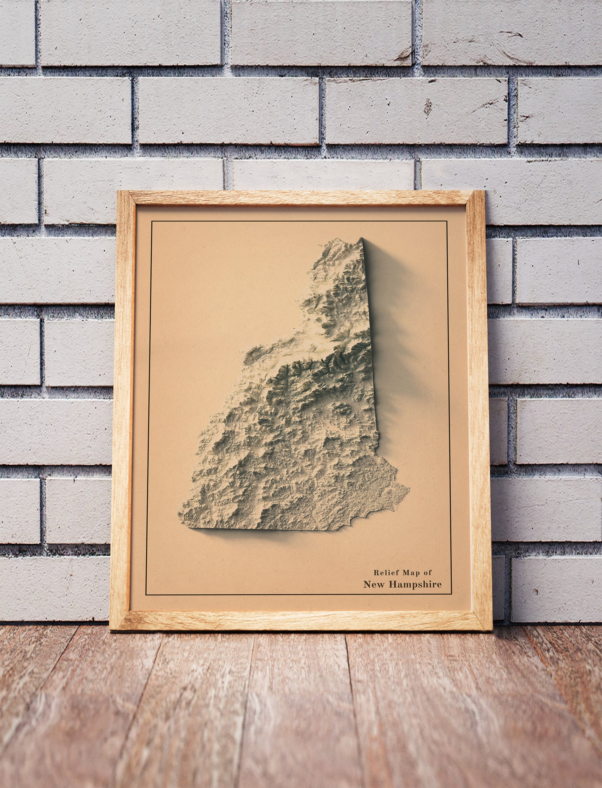 Vintage New Hampshire shaded relief map in a wooden frame. Realistic terrain art print for home decor, displayed against a brick wall