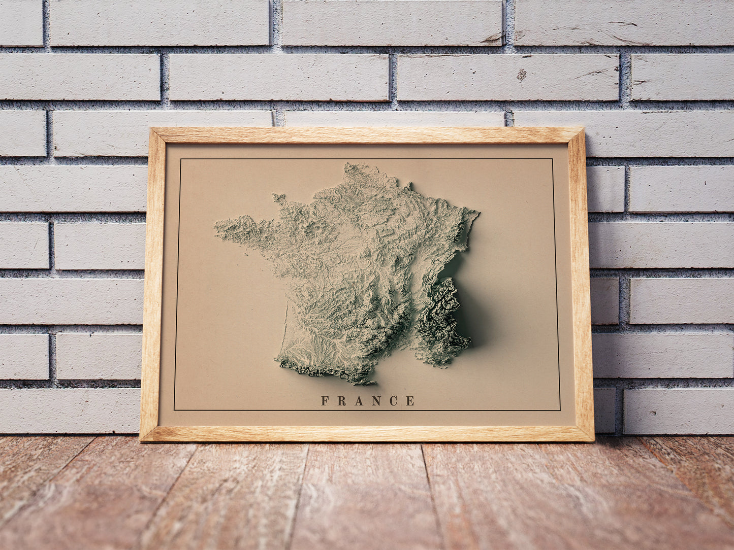 Vintage France shaded relief map in a wooden frame. Realistic terrain art print for home decor, displayed against a brick wall