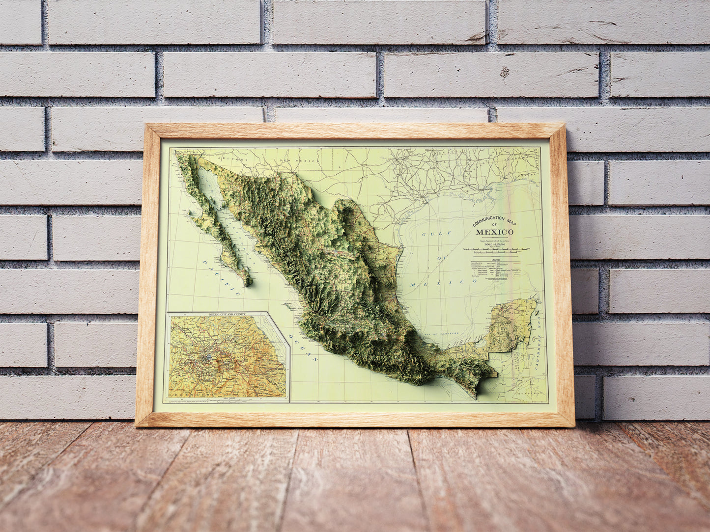 Vintage Mexico shaded relief map in a wooden frame. Realistic terrain art print for home decor, displayed against a brick wall