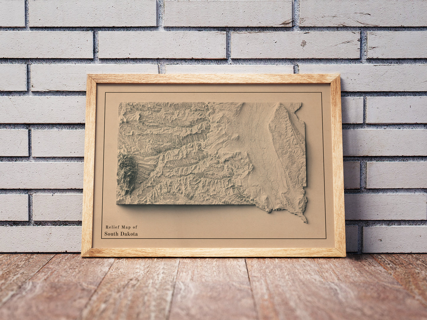 Vintage South Dakota shaded relief map in a wooden frame. Realistic terrain art print for home decor, displayed against a brick wall