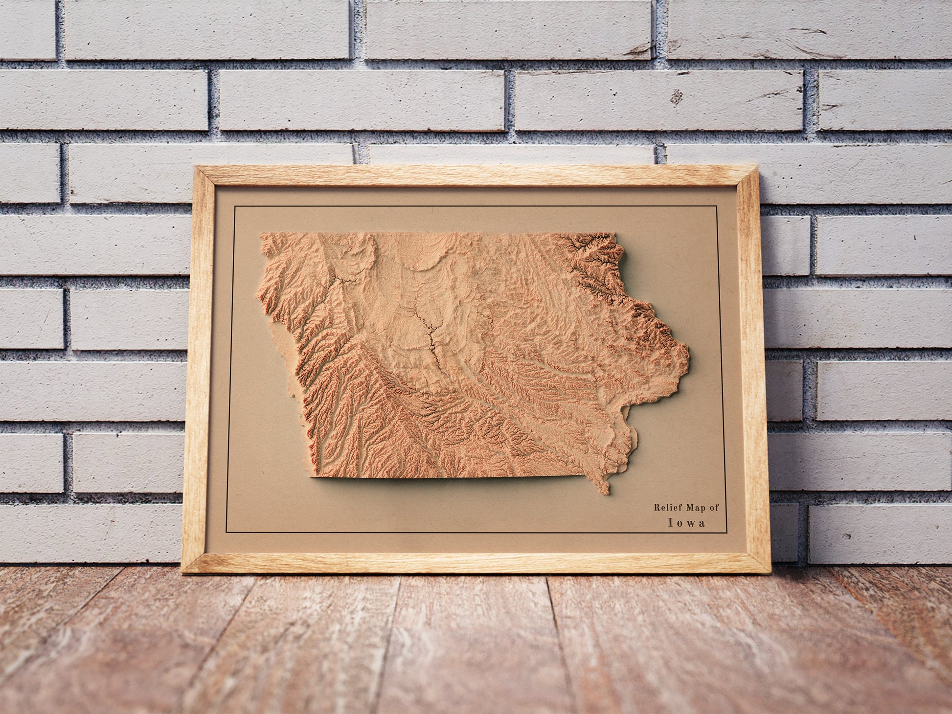 Vintage Iowa shaded relief map in a wooden frame. Realistic terrain art print for home decor, displayed against a brick wall