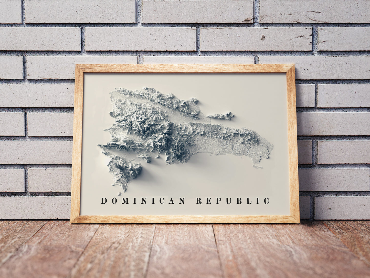 Dominican Republic shaded relief map in a wooden frame. Realistic terrain art print for home decor, displayed against a brick wall