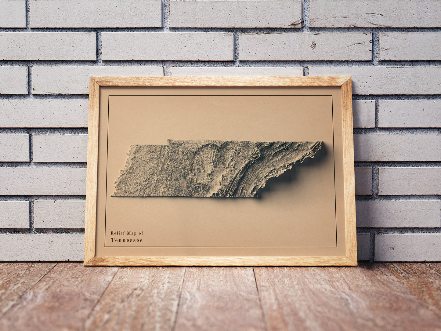 Vintage Tennessee shaded relief map in a wooden frame. Realistic terrain art print for home decor, displayed against a brick wall