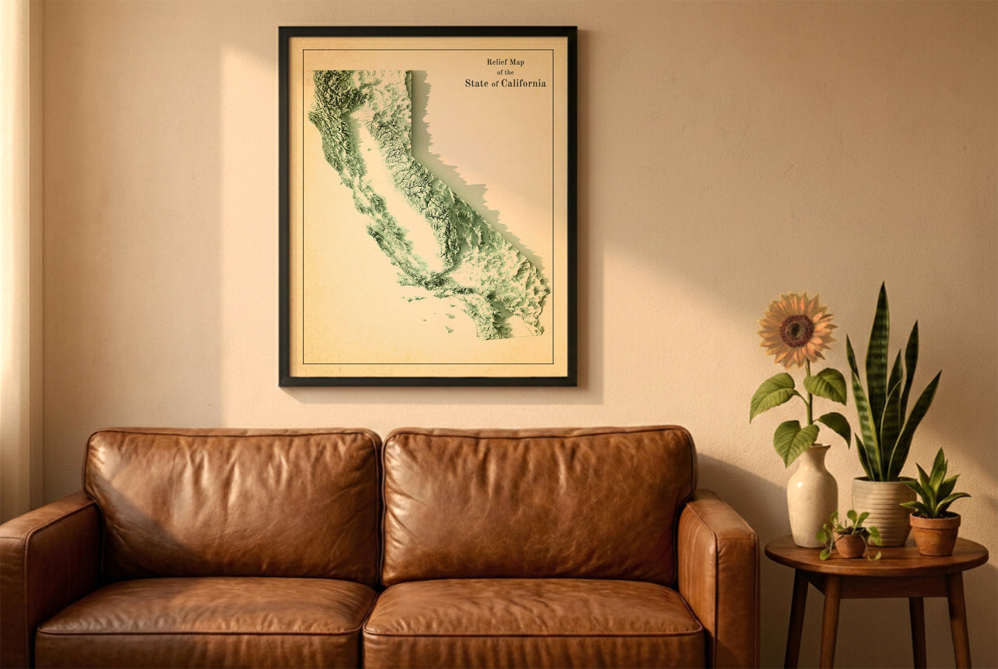 California vintage relief map in a black frame above a brown leather sofa. Boho living room with warm sunlight, sunflower, and indoor plants on a wooden side table