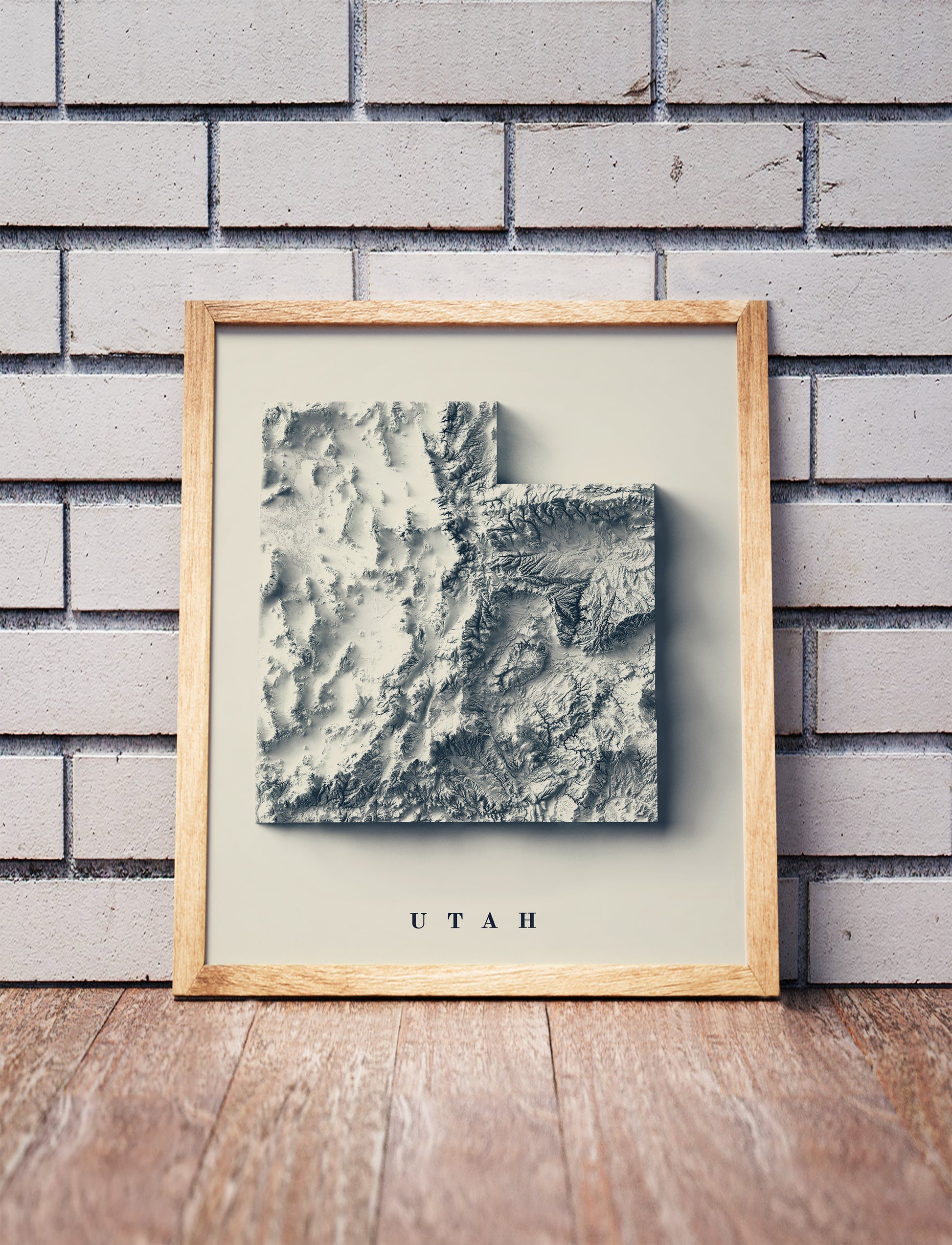 utah shaded relief map in a wooden frame. Realistic terrain art print for home decor, displayed against a brick wall