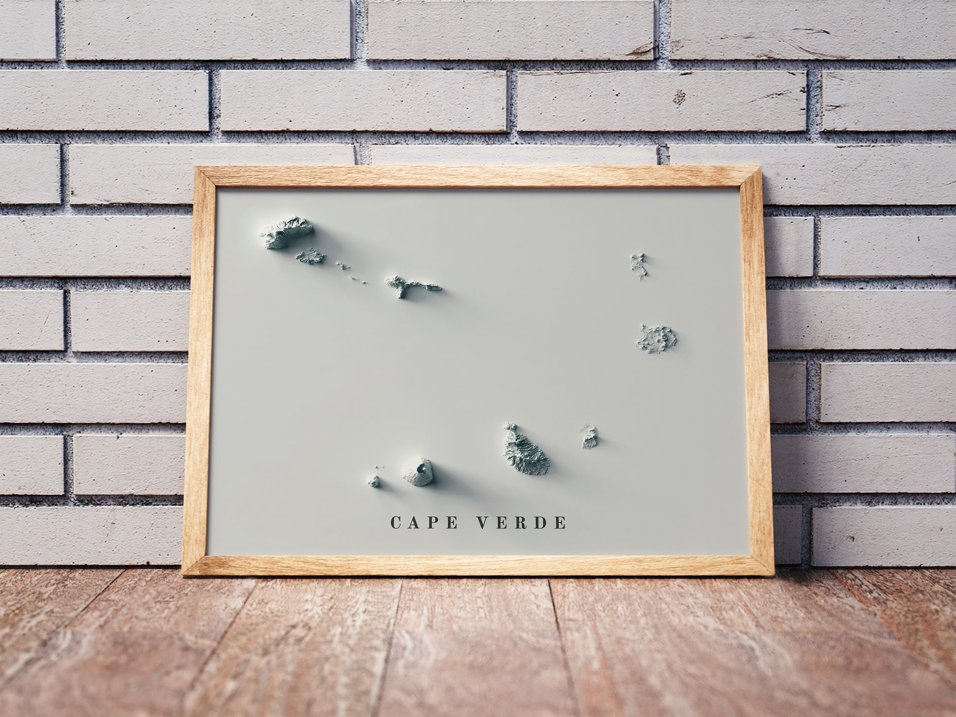 Cape Verde shaded relief map in a wooden frame. Realistic terrain art print for home decor, displayed against a brick wall