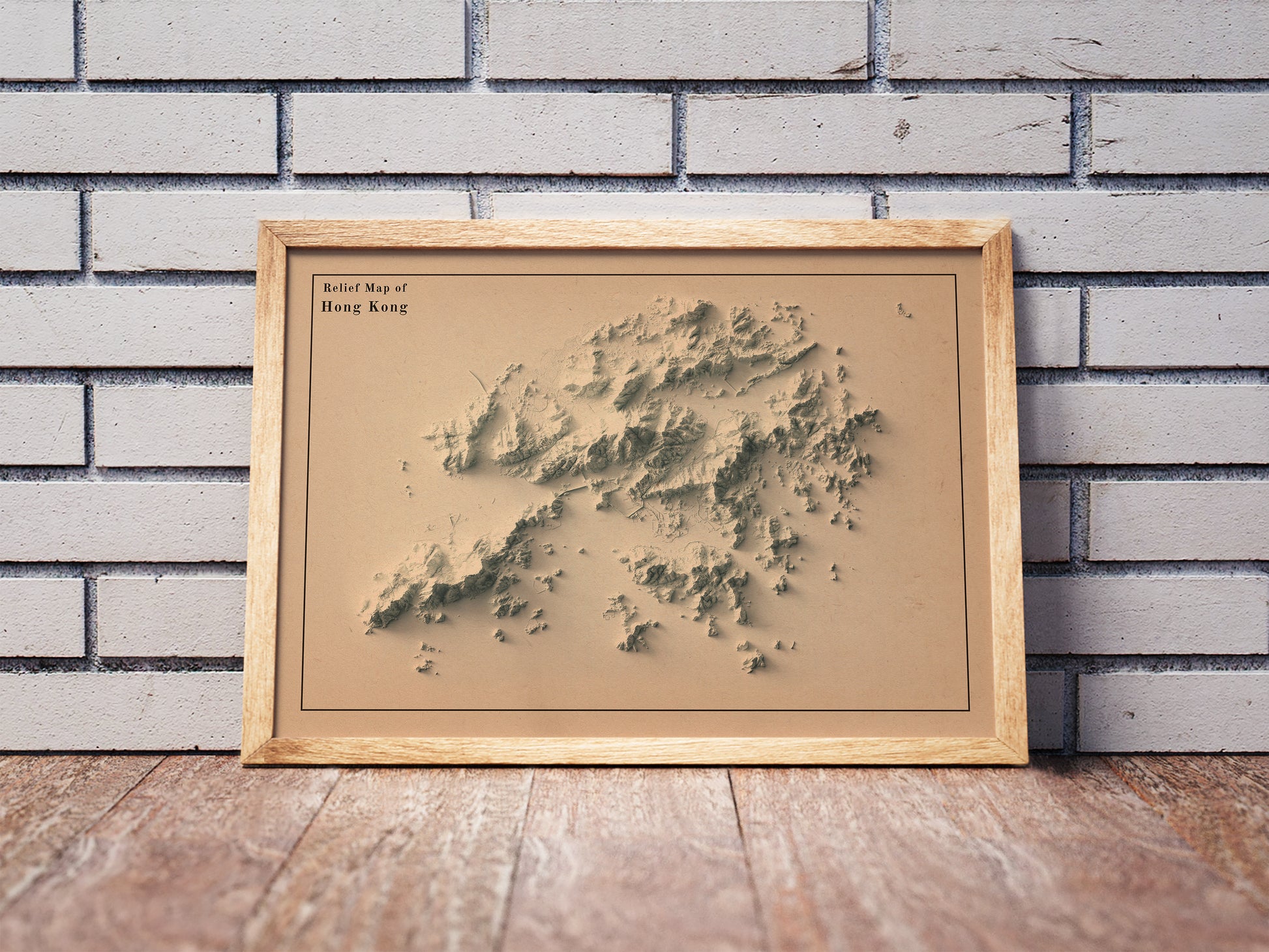 Vintage Hong Kong shaded relief map in a wooden frame. Realistic terrain art print for home decor, displayed against a brick wall