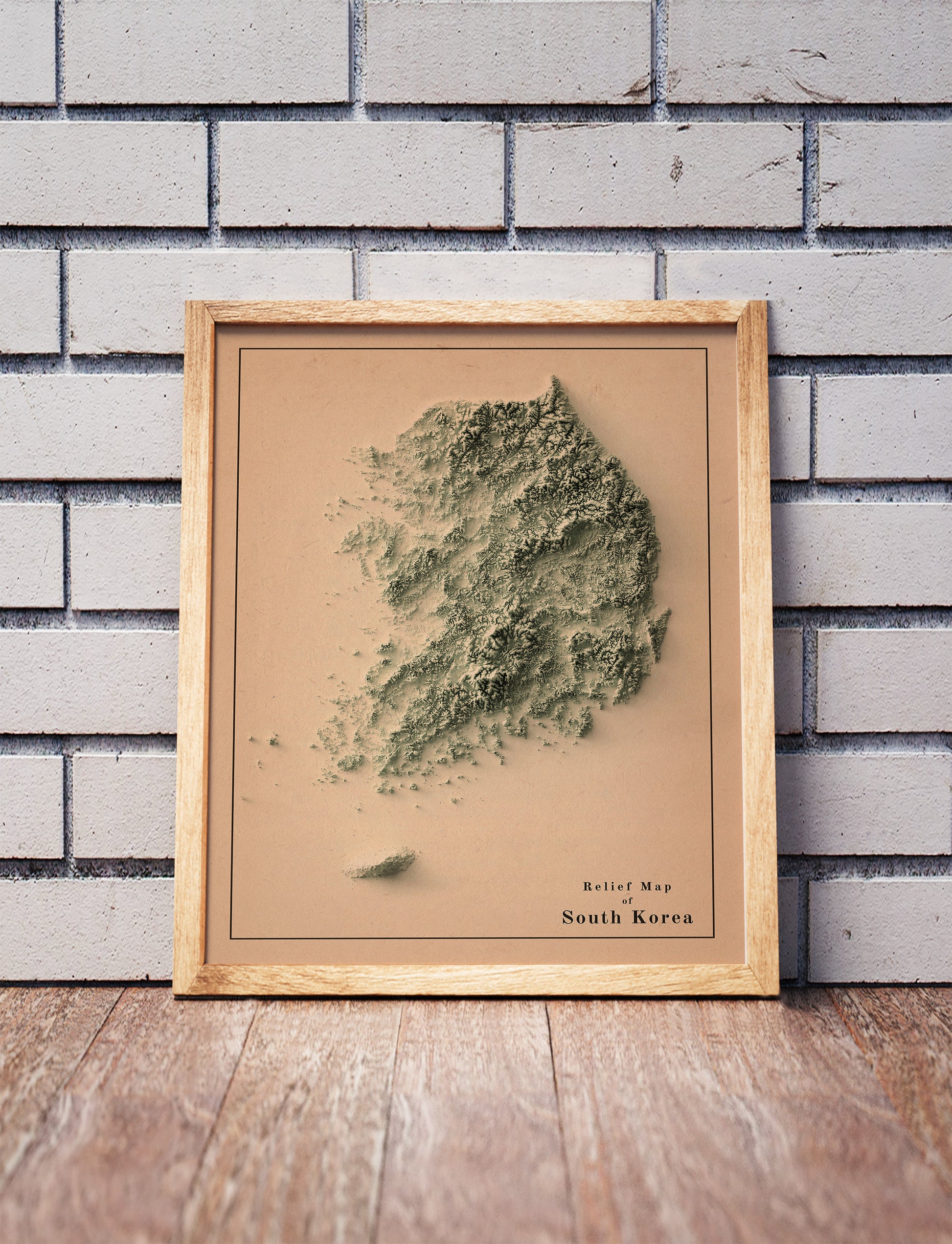 Vintage South Korea shaded relief map in a wooden frame. Realistic terrain art print for home decor, displayed against a brick wall