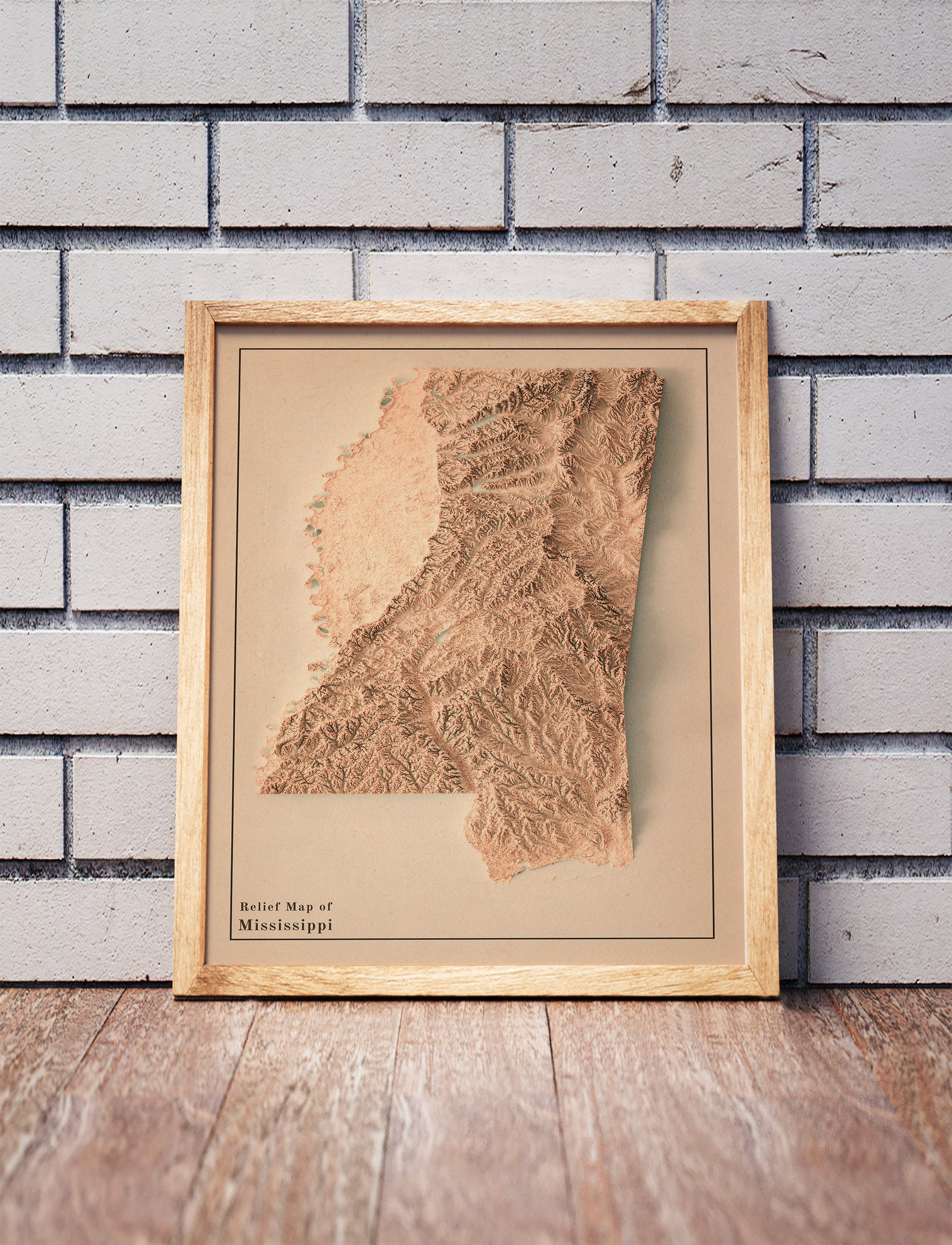 Vintage Mississippi shaded relief map in a wooden frame. Realistic terrain art print for home decor, displayed against a brick wall