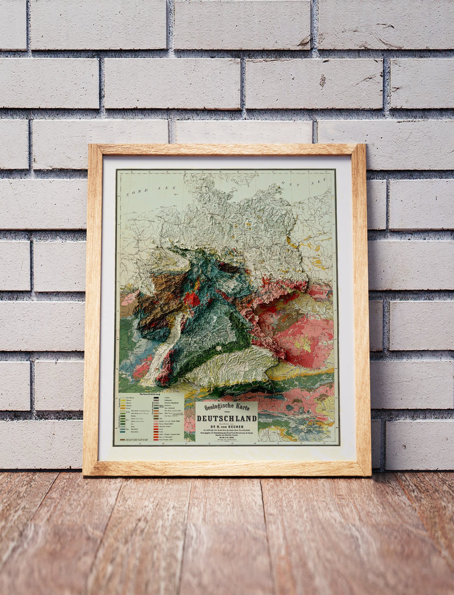 Vintage Germany shaded relief map in a wooden frame. Realistic terrain art print for home decor, displayed against a brick wall