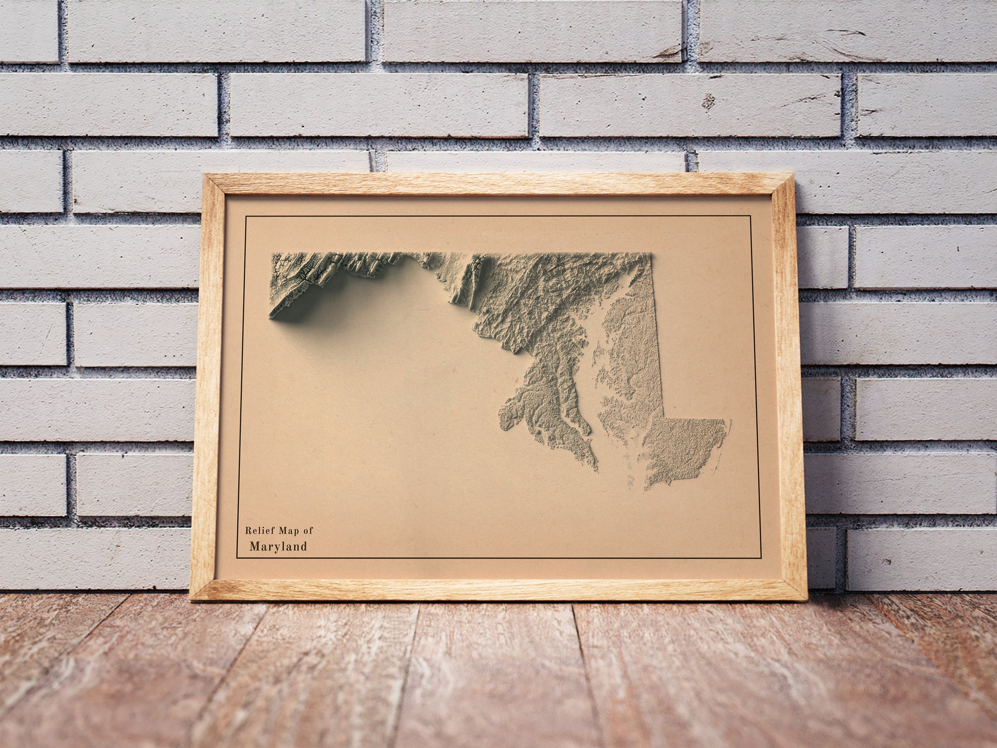 Vintage Maryland shaded relief map in a wooden frame. Realistic terrain art print for home decor, displayed against a brick wall