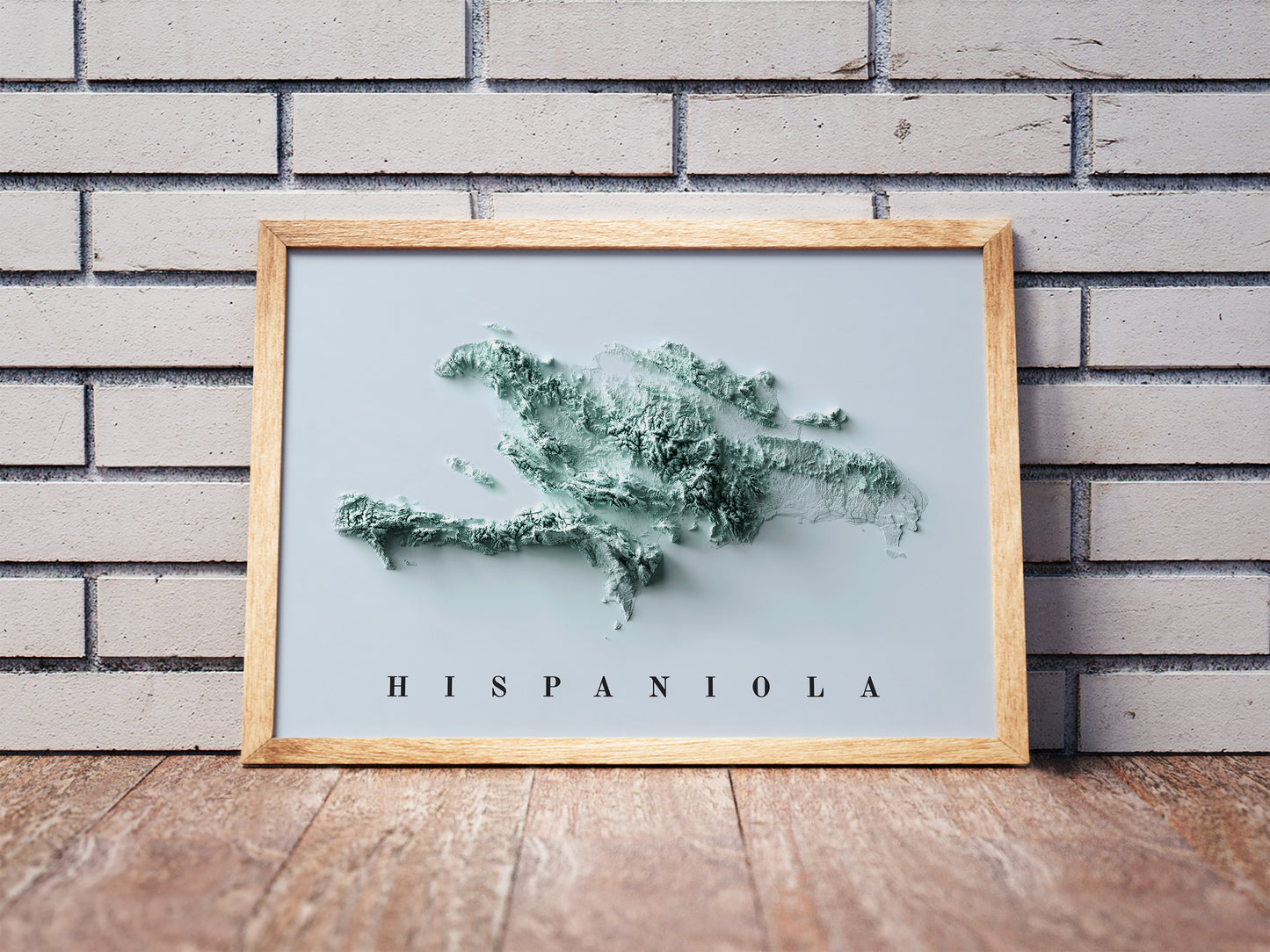 Hispaniola Island shaded relief map in a wooden frame. Realistic terrain art print for home decor, displayed against a brick wall