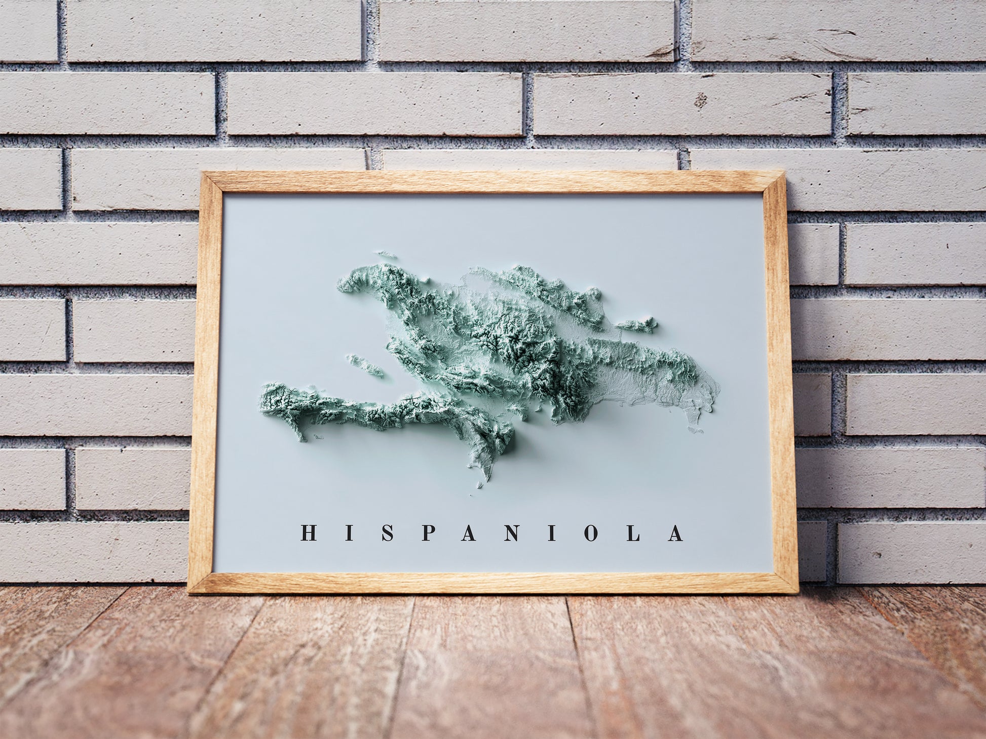 Hispaniola Island shaded relief map in a wooden frame. Realistic terrain art print for home decor, displayed against a brick wall