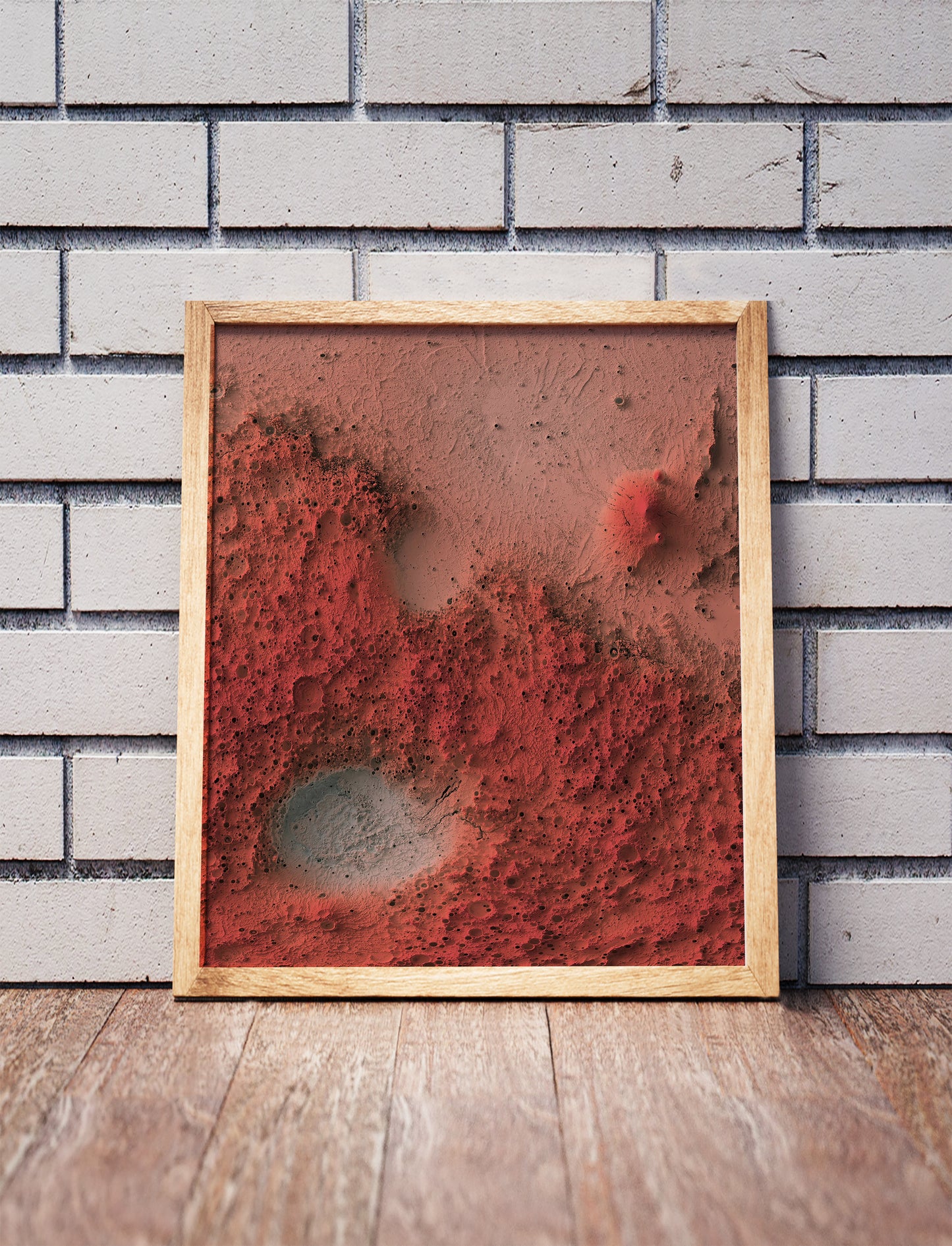 Mars shaded relief map in a wooden frame. Realistic terrain art print for home decor, displayed against a brick wall