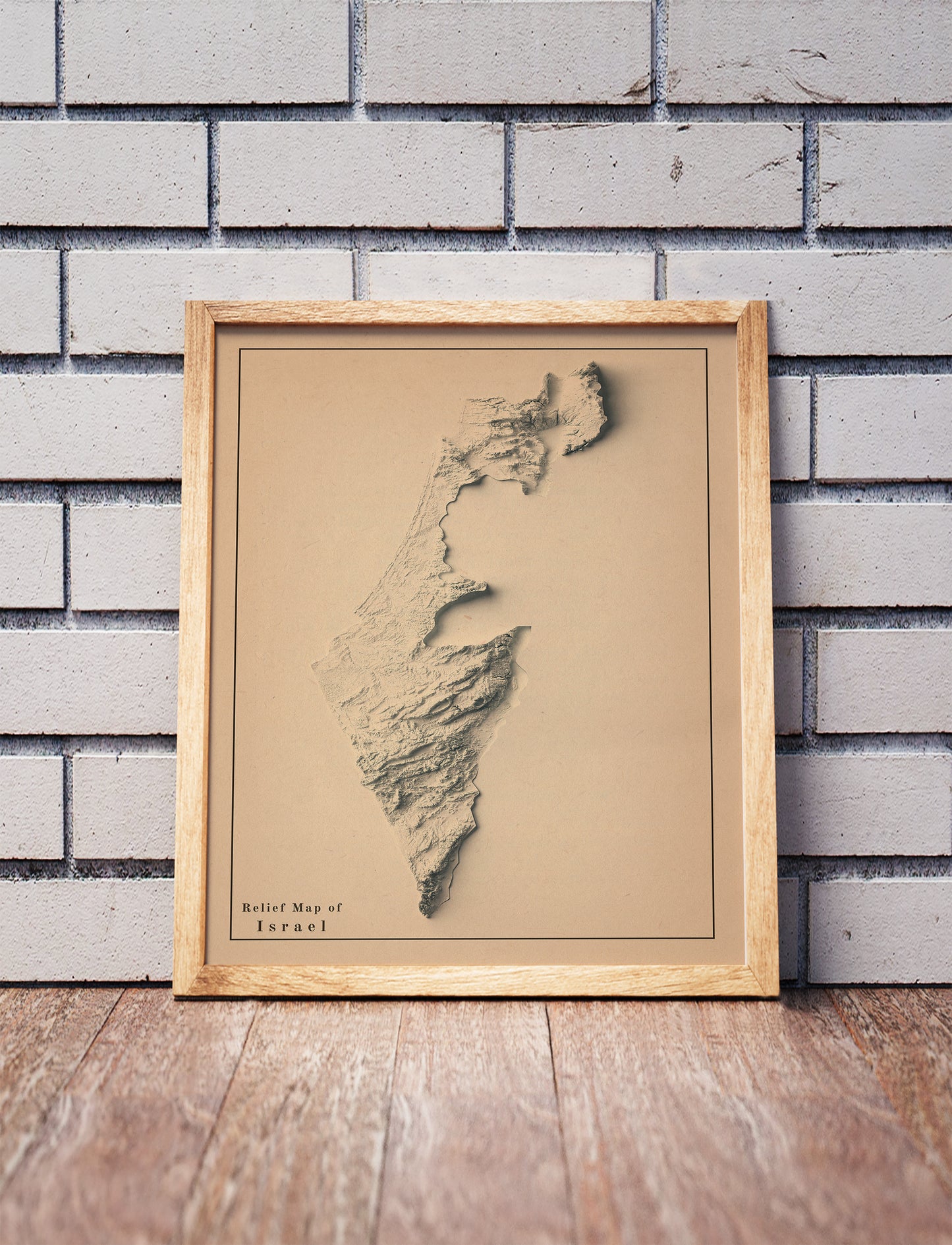 Vintage Israel shaded relief map in a wooden frame. Realistic terrain art print for home decor, displayed against a brick wall