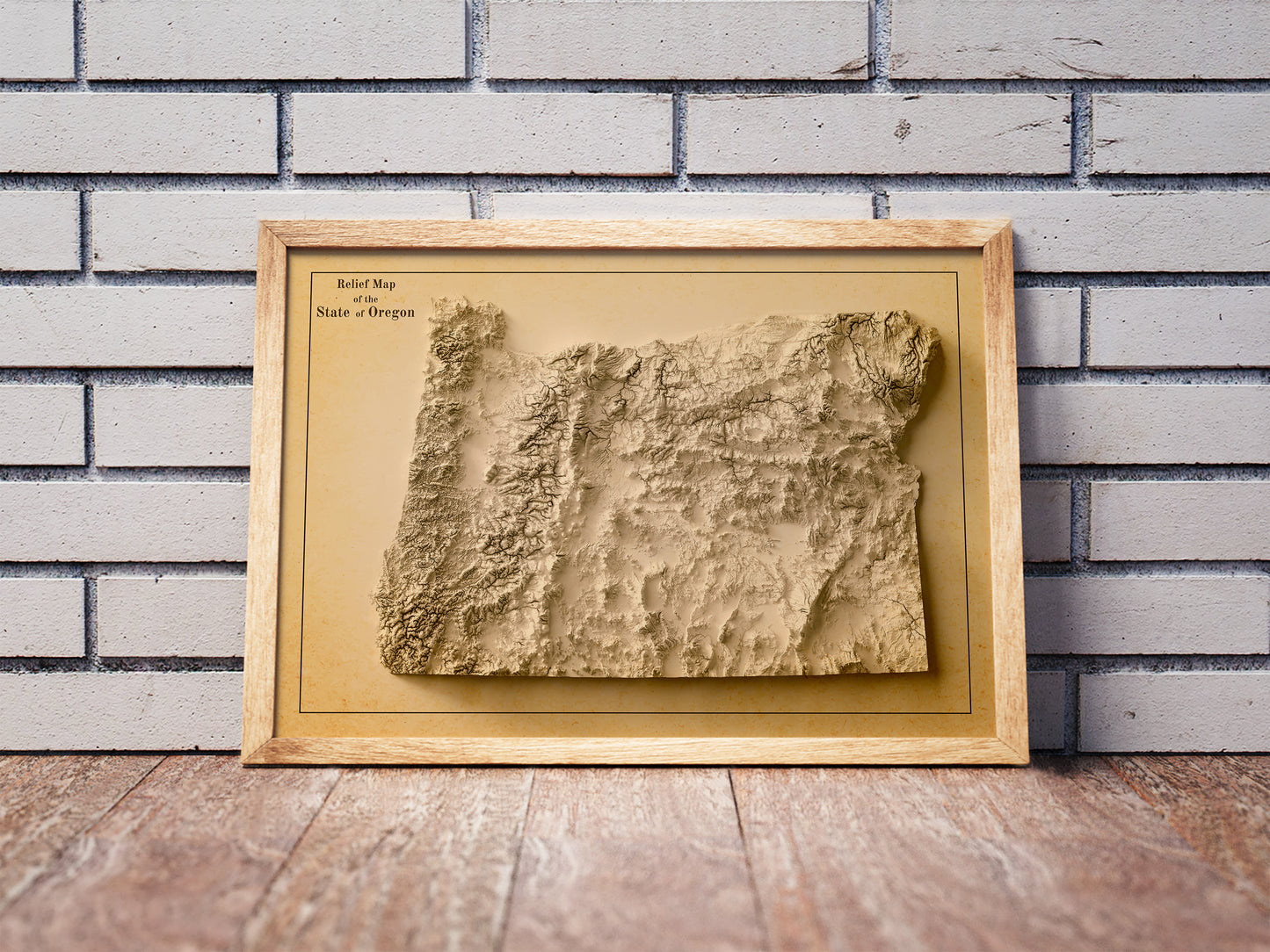 Vintage Oregon shaded relief map in a wooden frame. Realistic terrain art print for home decor, displayed against a brick wall