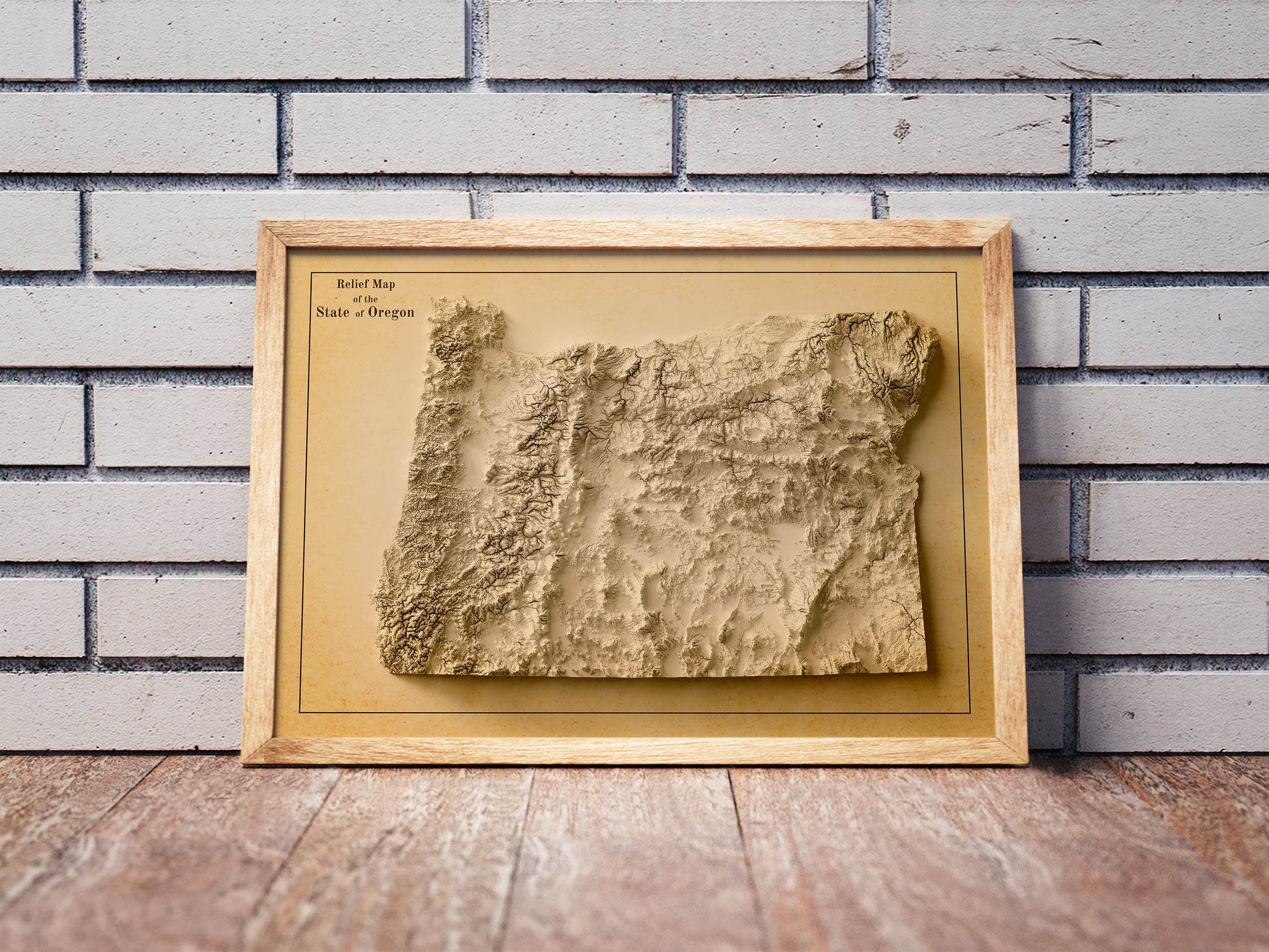 Vintage Oregon shaded relief map in a wooden frame. Realistic terrain art print for home decor, displayed against a brick wall