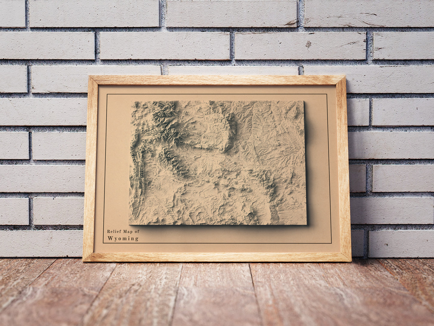Vintage Wyoming shaded relief map in a wooden frame. Realistic terrain art print for home decor, displayed against a brick wall