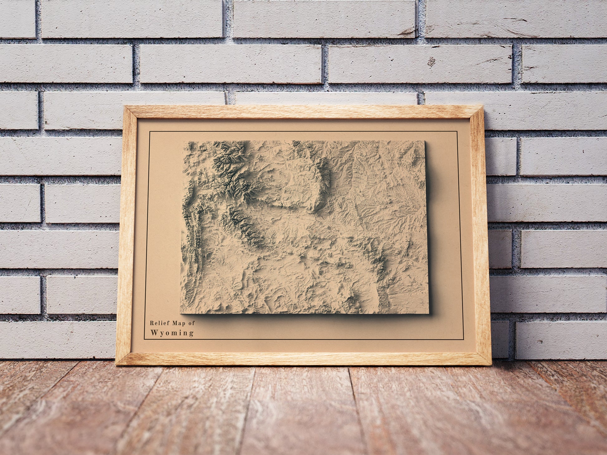 Vintage Wyoming shaded relief map in a wooden frame. Realistic terrain art print for home decor, displayed against a brick wall