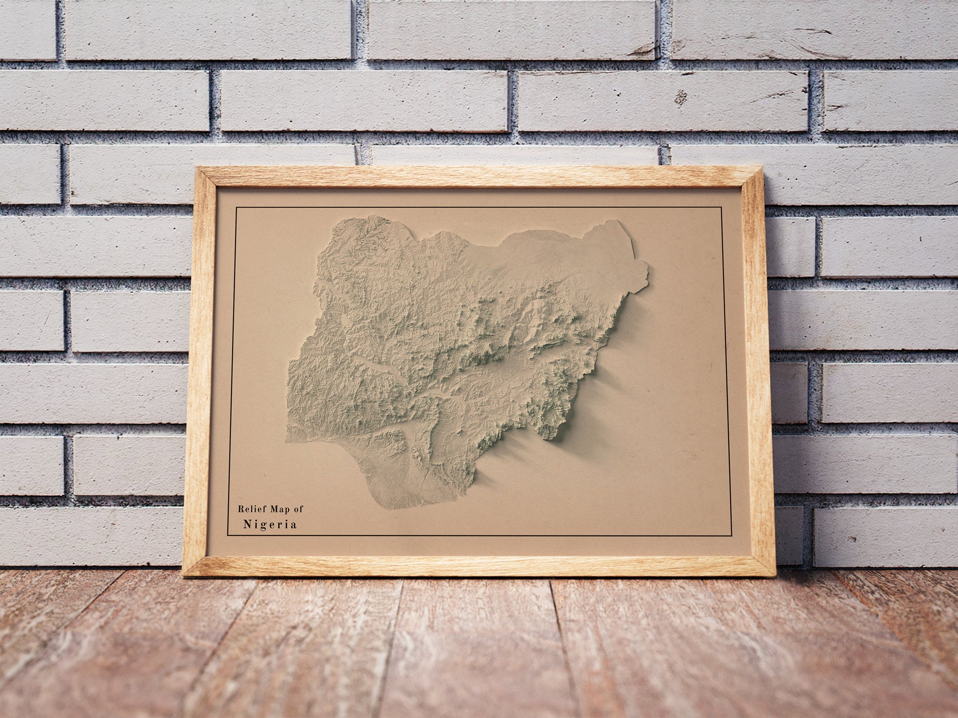 Vintage Nigeria shaded relief map in a wooden frame. Realistic terrain art print for home decor, displayed against a brick wall