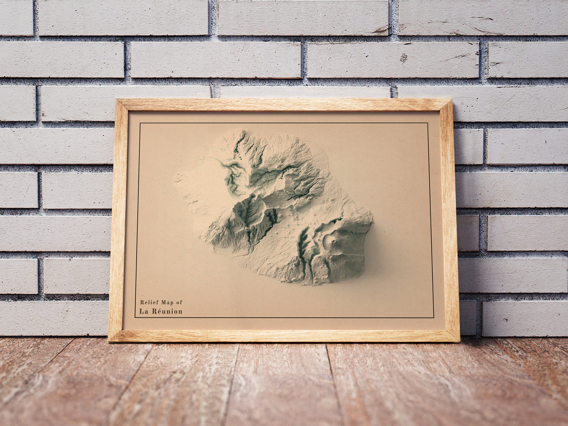Vintage Reunion, France, shaded relief map in a wooden frame. Realistic terrain art print for home decor, displayed against a brick wall