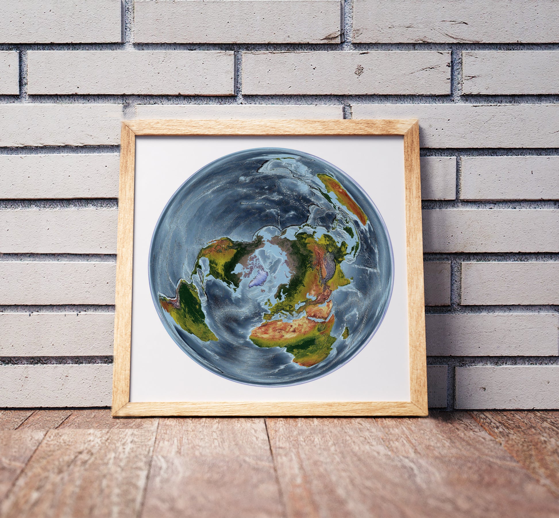 WGS 1984 Grid North projection shaded relief world map in a wooden frame. Realistic terrain art print for home decor, displayed against a brick wall