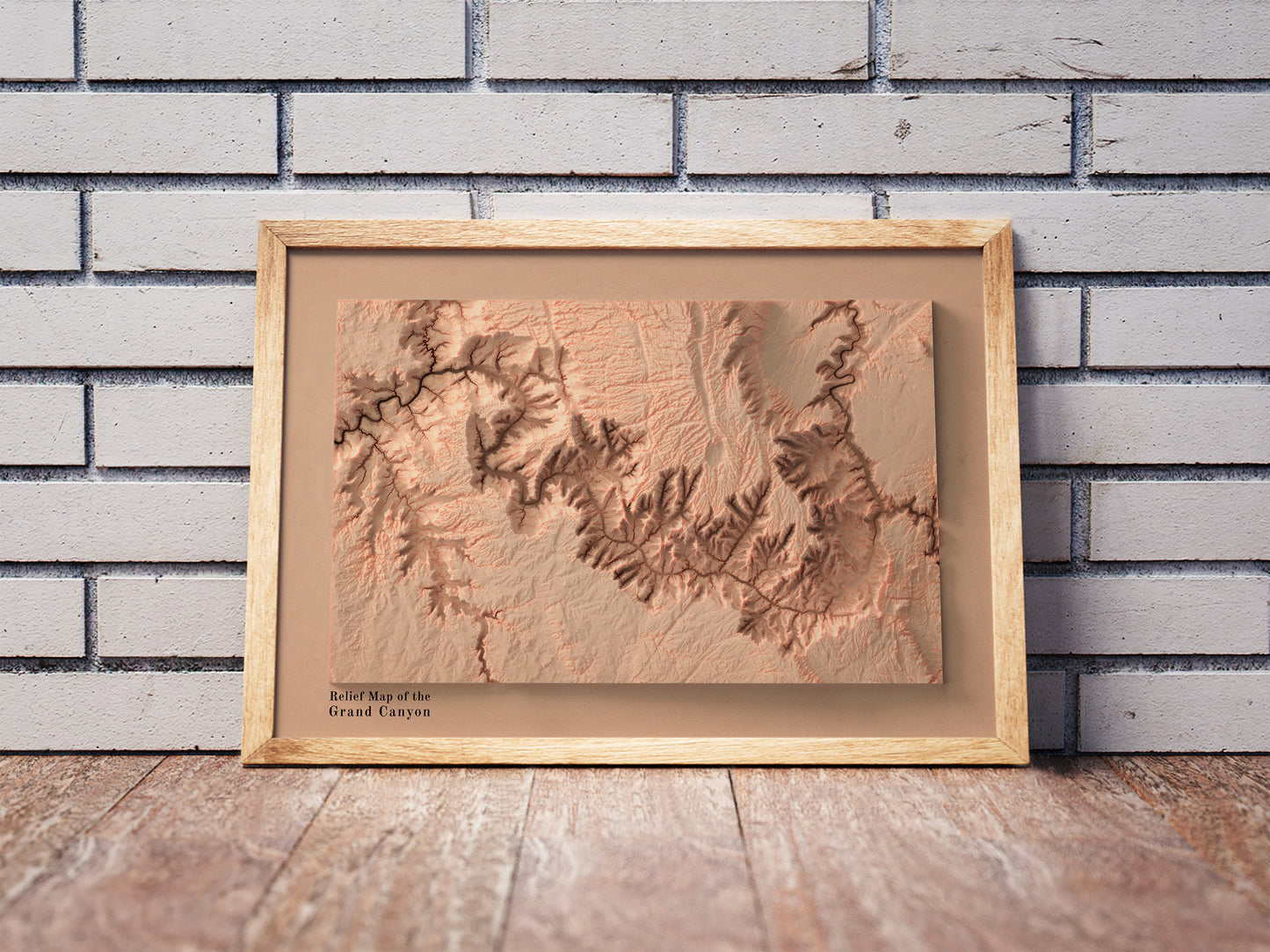 Vintage Grand Canyon shaded relief map in a wooden frame. Realistic terrain art print for home decor, displayed against a brick wall