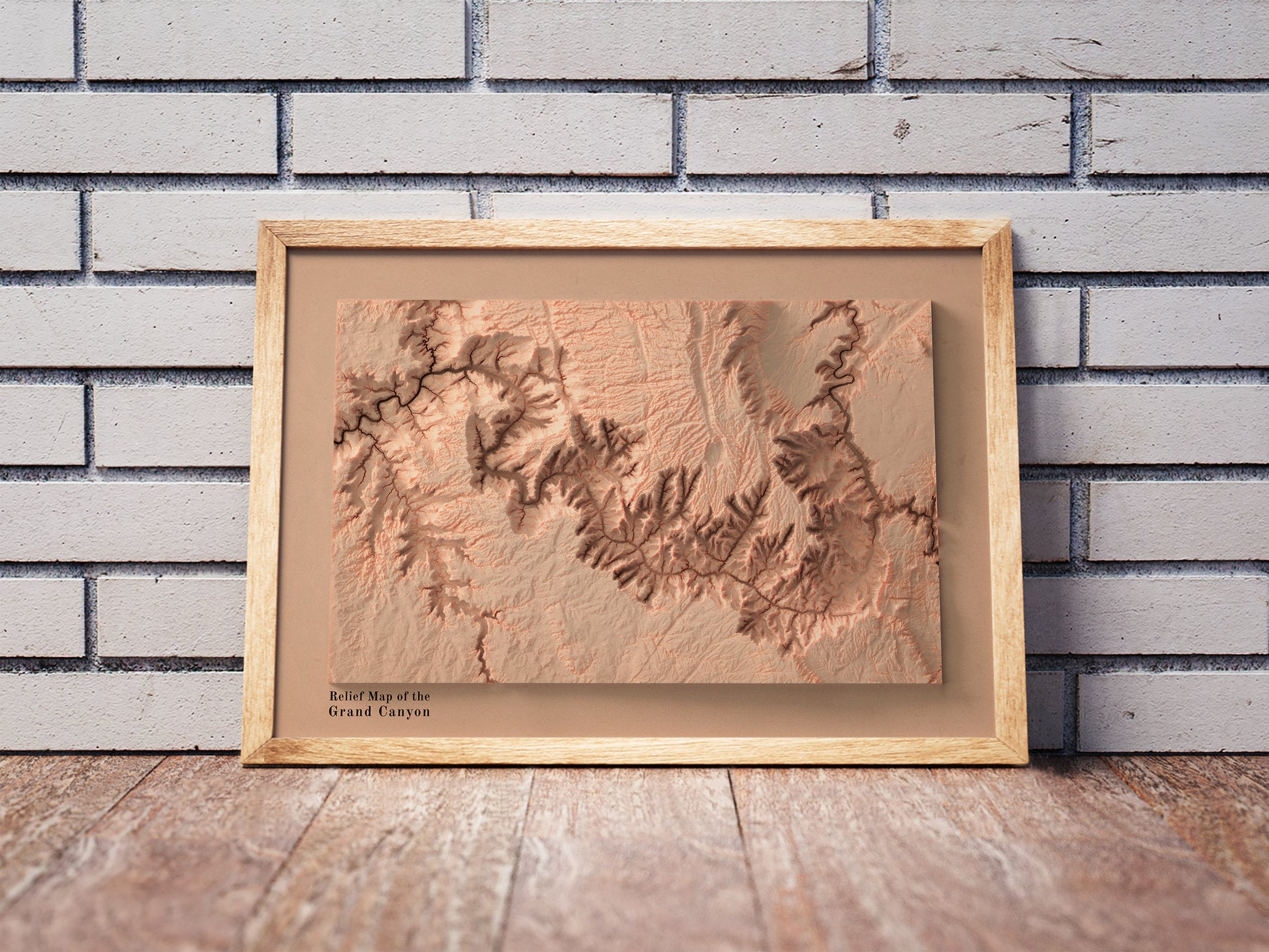 Vintage Grand Canyon shaded relief map in a wooden frame. Realistic terrain art print for home decor, displayed against a brick wall