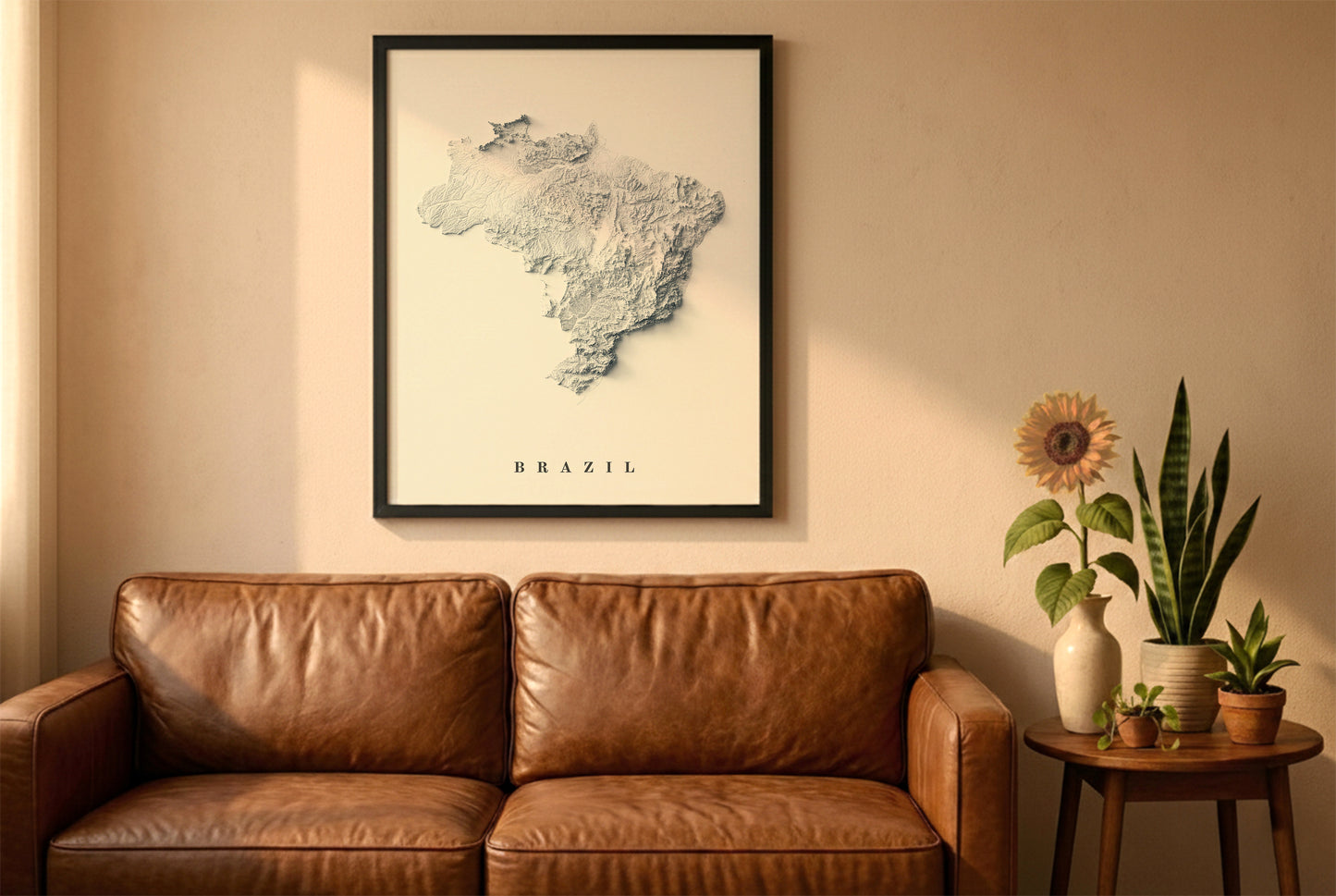 Brazil relief map in a black frame above a brown leather sofa. Boho living room with warm sunlight, sunflower, and indoor plants on a wooden side table