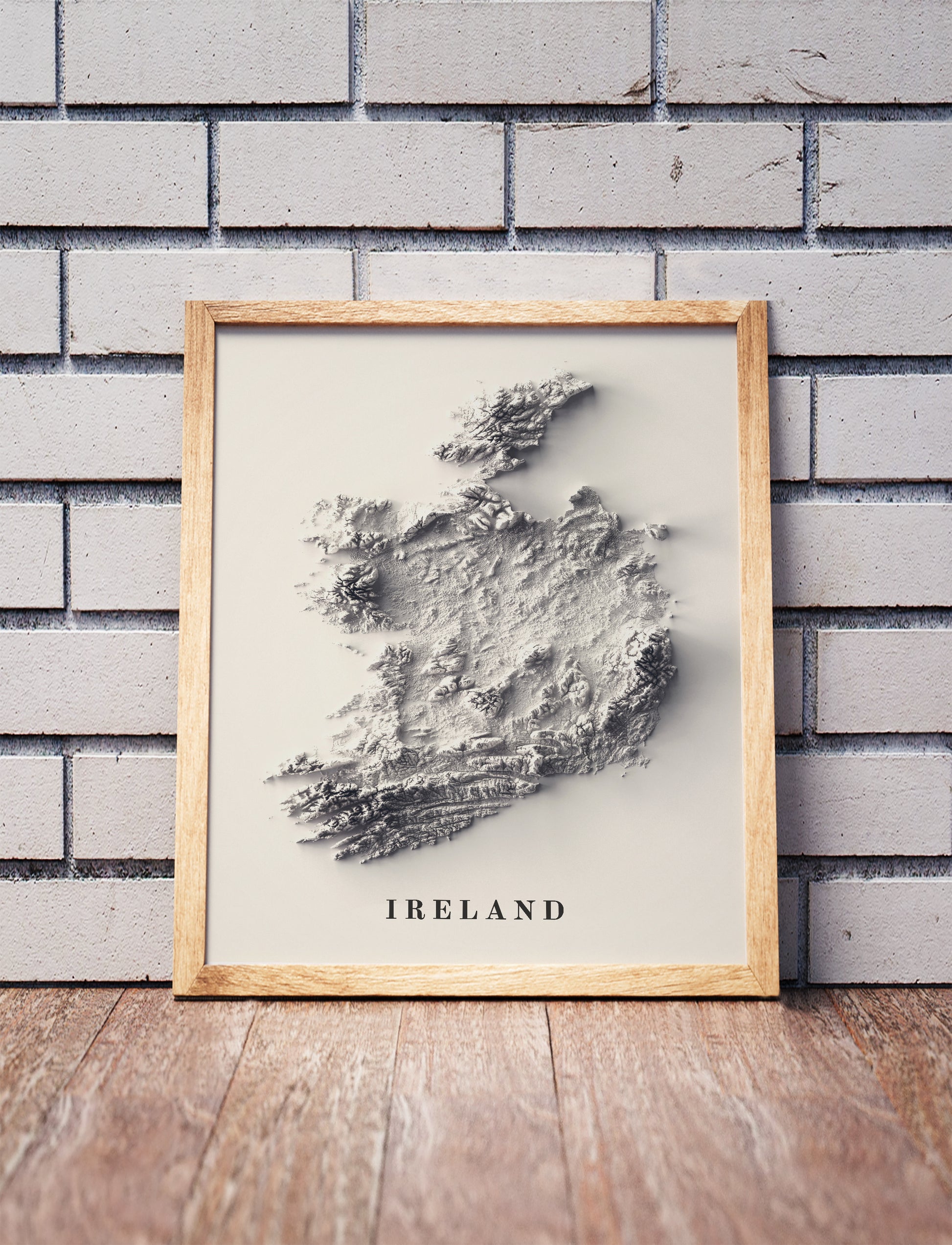 Ireland shaded relief map in a wooden frame. Realistic terrain art print for home decor, displayed against a brick wall