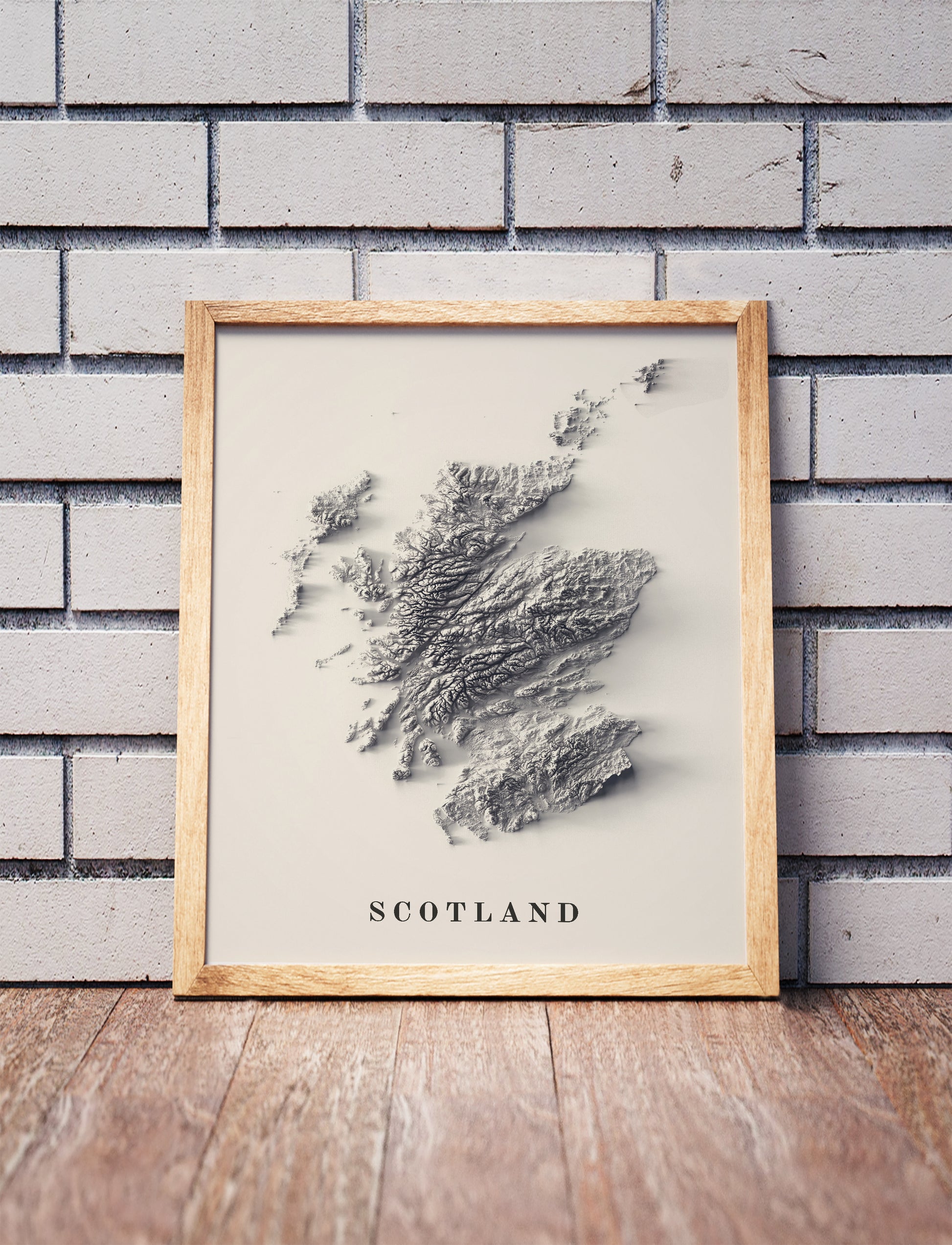 Scotland shaded relief map in a wooden frame. Realistic terrain art print for home decor, displayed against a brick wall