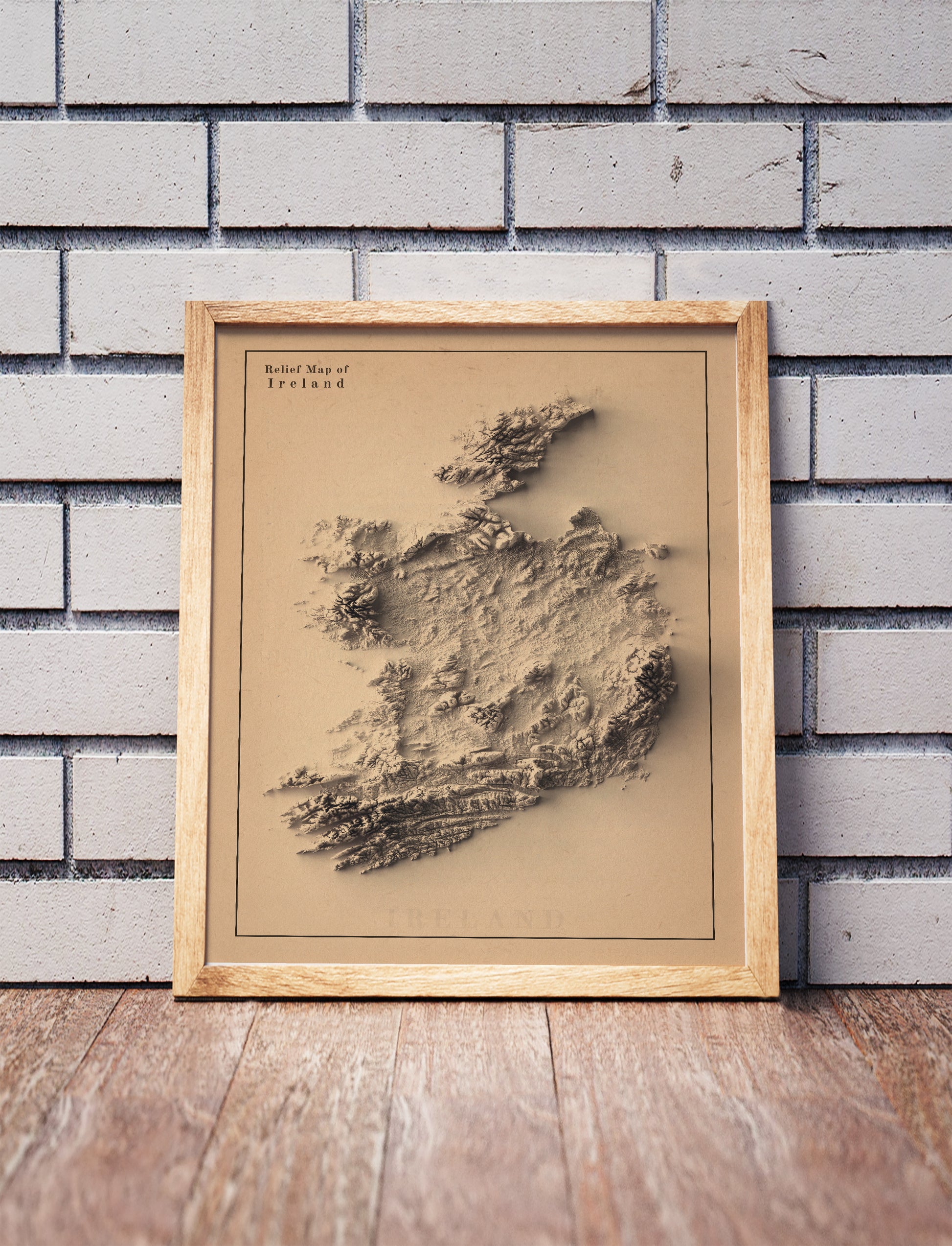 Ireland shaded relief map in a wooden frame. Realistic terrain art print for home decor, displayed against a brick wall
