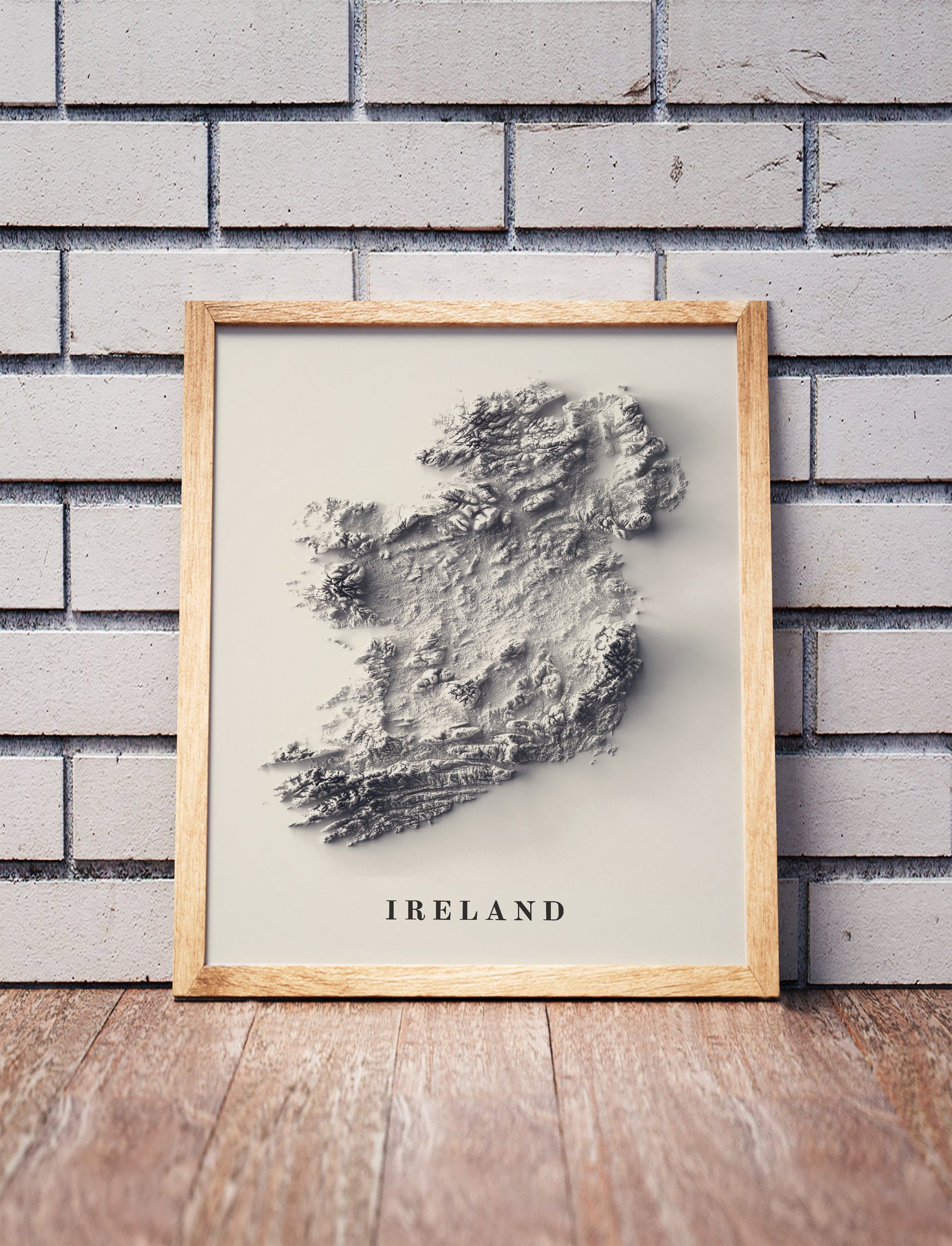 Ireland shaded relief map in a wooden frame. Realistic terrain art print for home decor, displayed against a brick wall