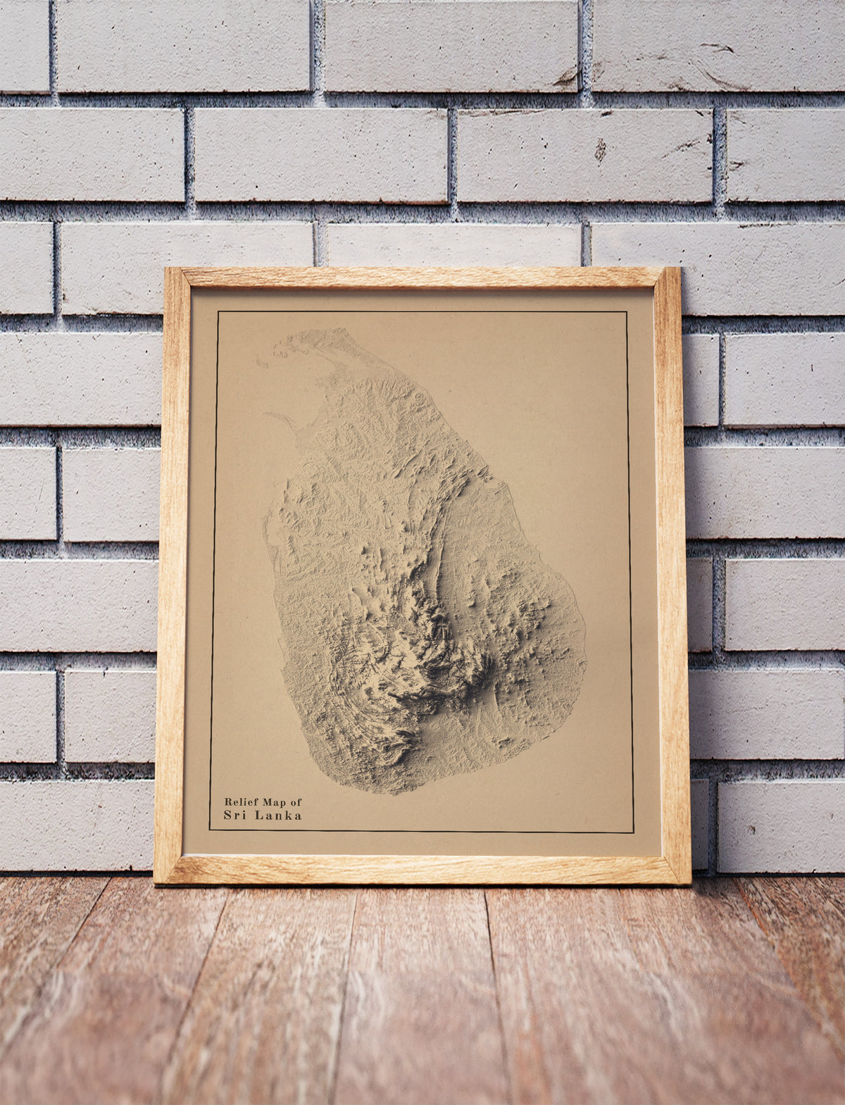 Vintage Sri Lanka shaded relief map in a wooden frame. Realistic terrain art print for home decor, displayed against a brick wall