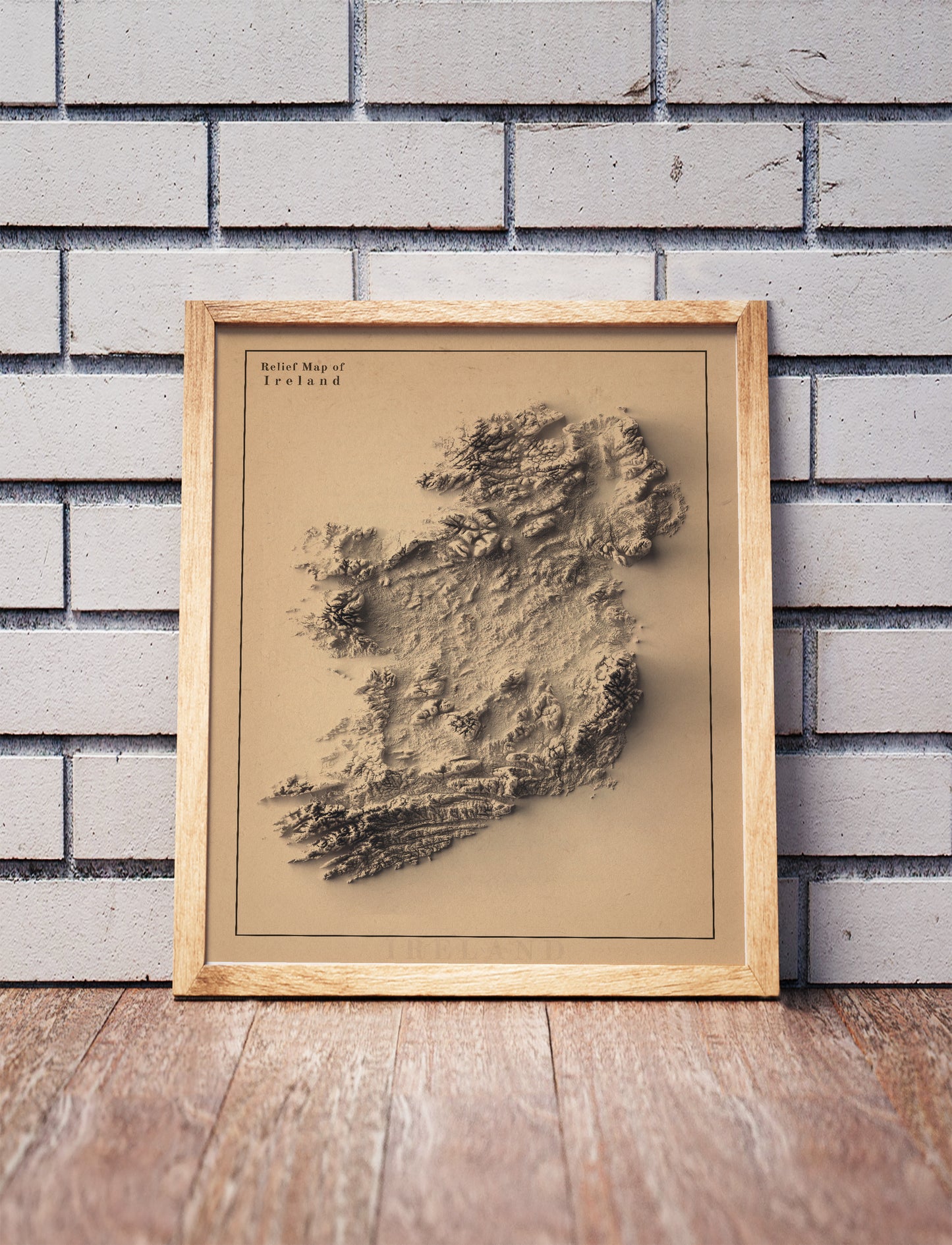Ireland shaded relief map in a wooden frame. Realistic terrain art print for home decor, displayed against a brick wall