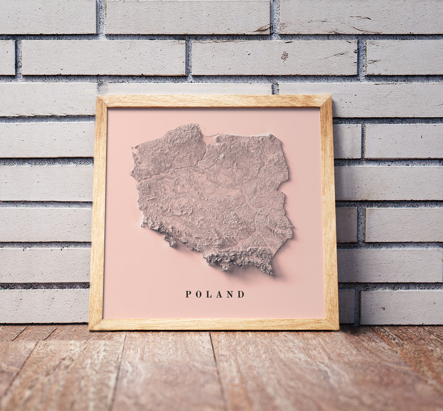 Poland shaded relief map in a wooden frame. Realistic terrain art print for home decor, displayed against a brick wall