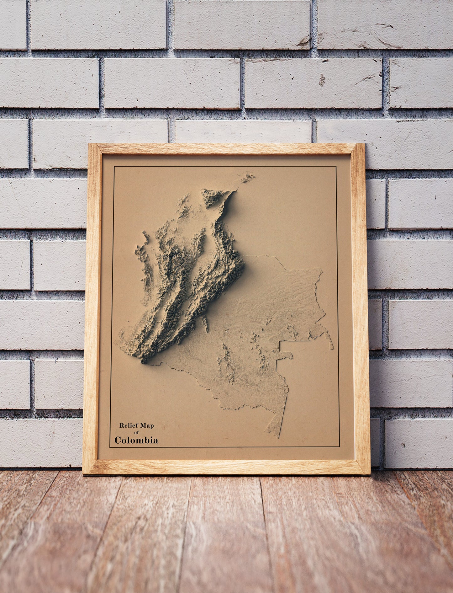 Vintage Colombia shaded relief map in a wooden frame. Realistic terrain art print for home decor, displayed against a brick wall