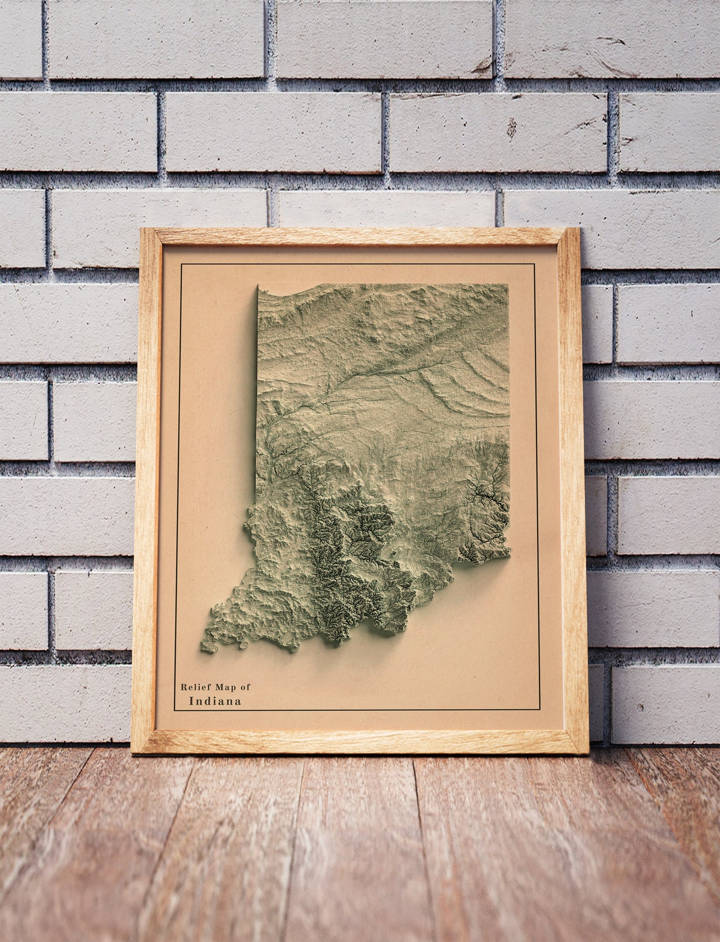 Vintage Indiana shaded relief map in a wooden frame. Realistic terrain art print for home decor, displayed against a brick wall