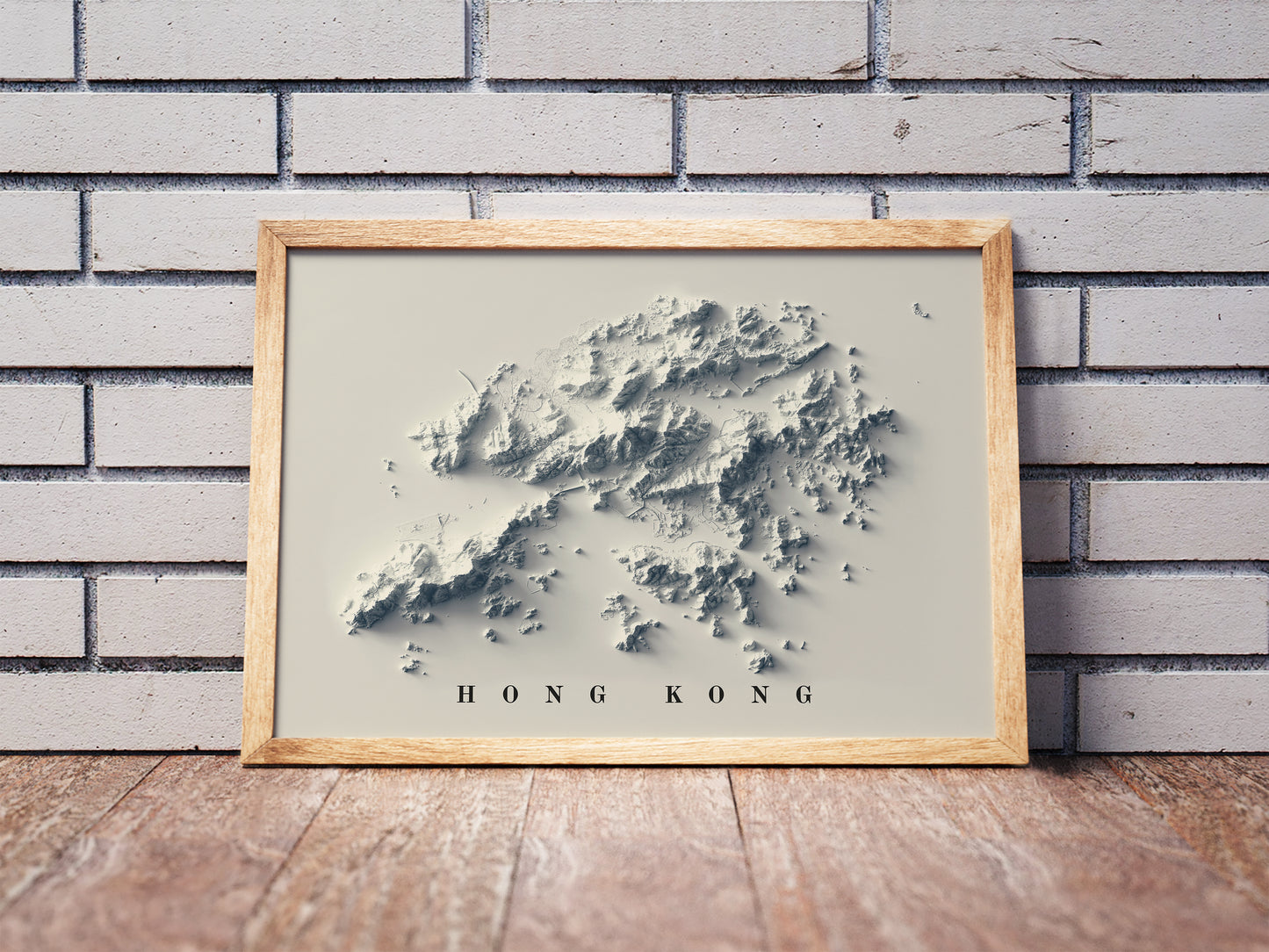 Hong Kong shaded relief map in a wooden frame. Realistic terrain art print for home decor, displayed against a brick wall