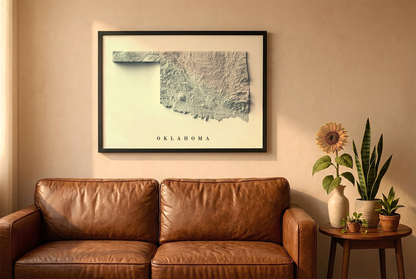 Oklahoma relief map in a black frame above a brown leather sofa. Boho living room with warm sunlight, sunflower, and indoor plants on a wooden side table