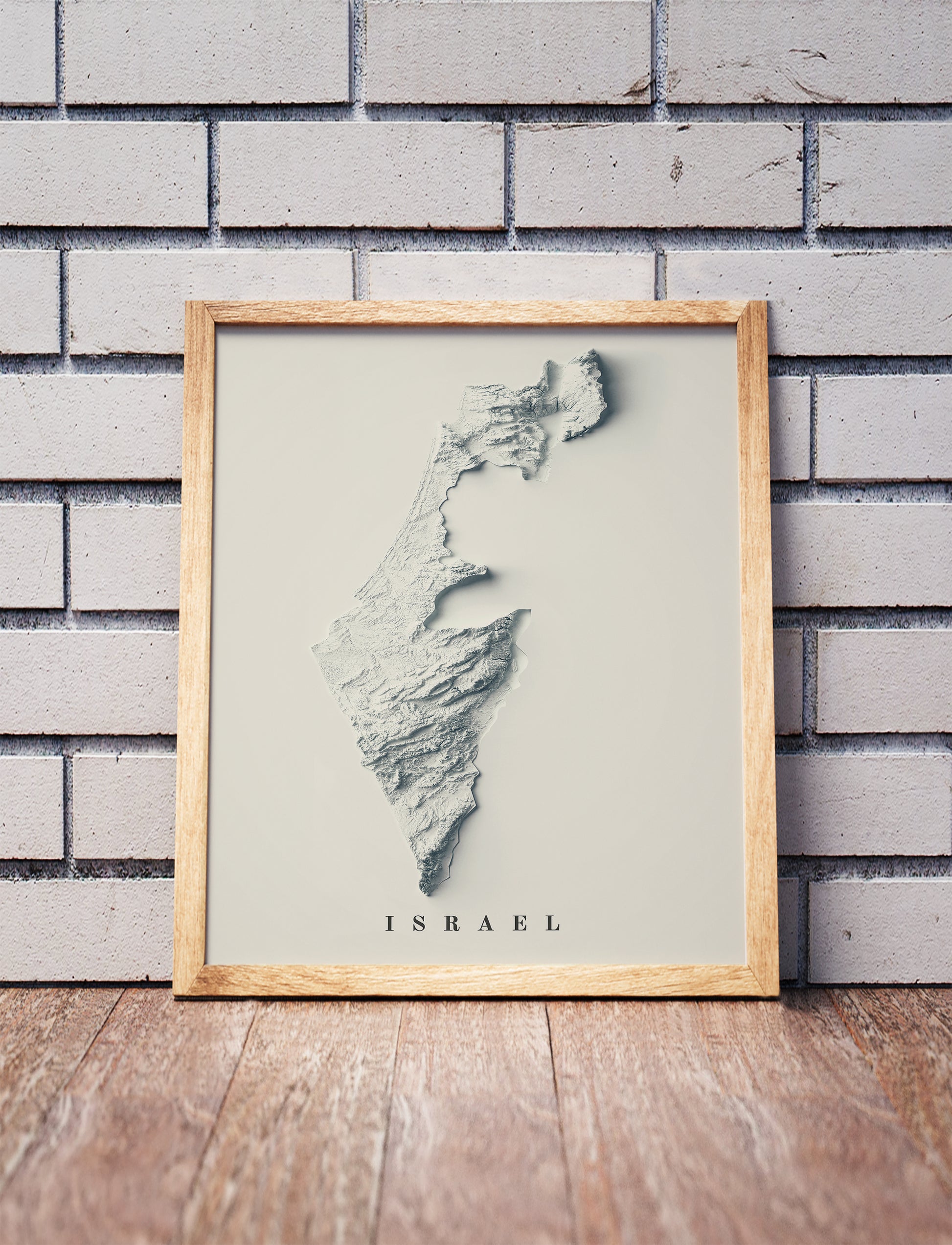 Israel shaded relief map in a wooden frame. Realistic terrain art print for home decor, displayed against a brick wall