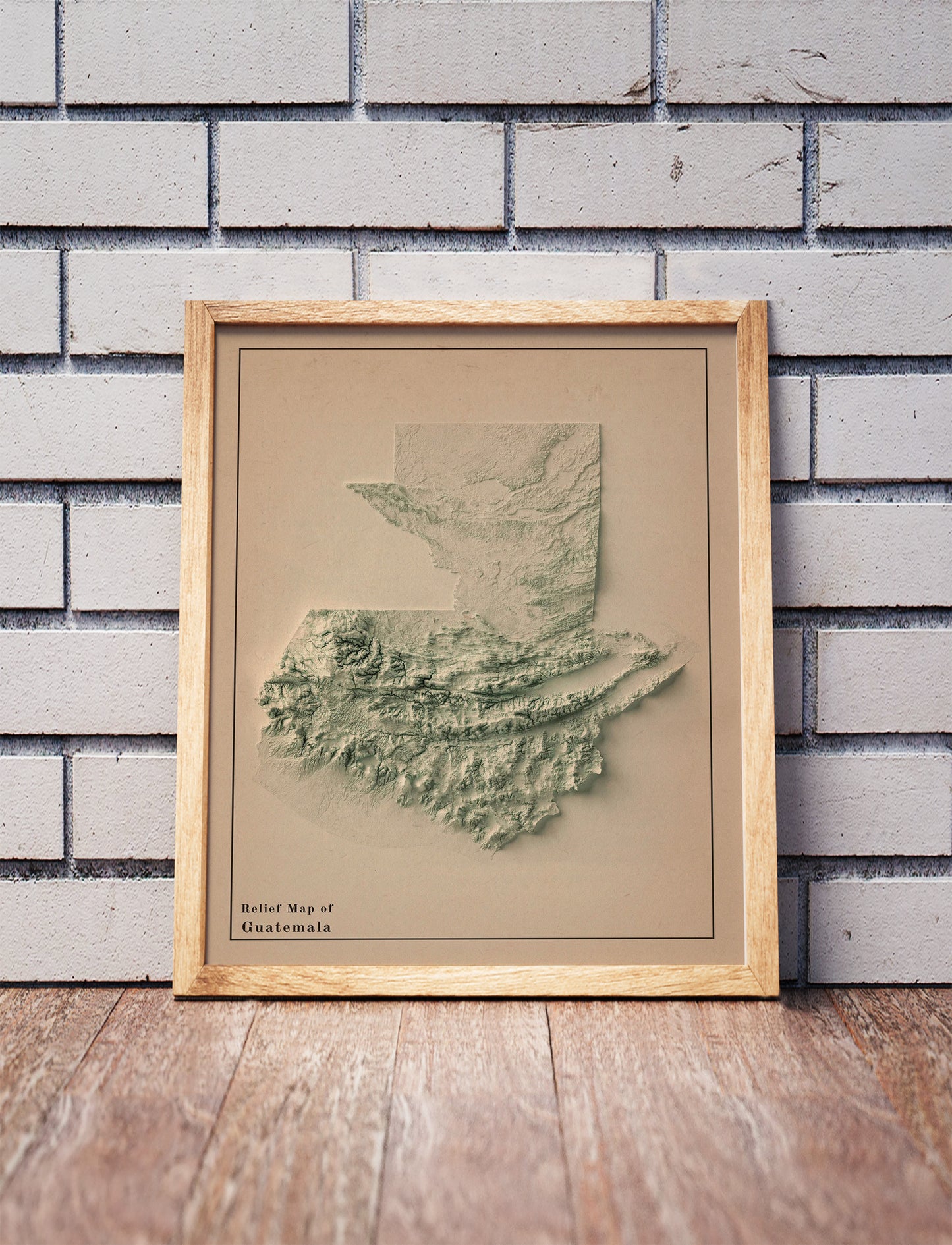 Vintage Guatemala shaded relief map in a wooden frame. Realistic terrain art print for home decor, displayed against a brick wall