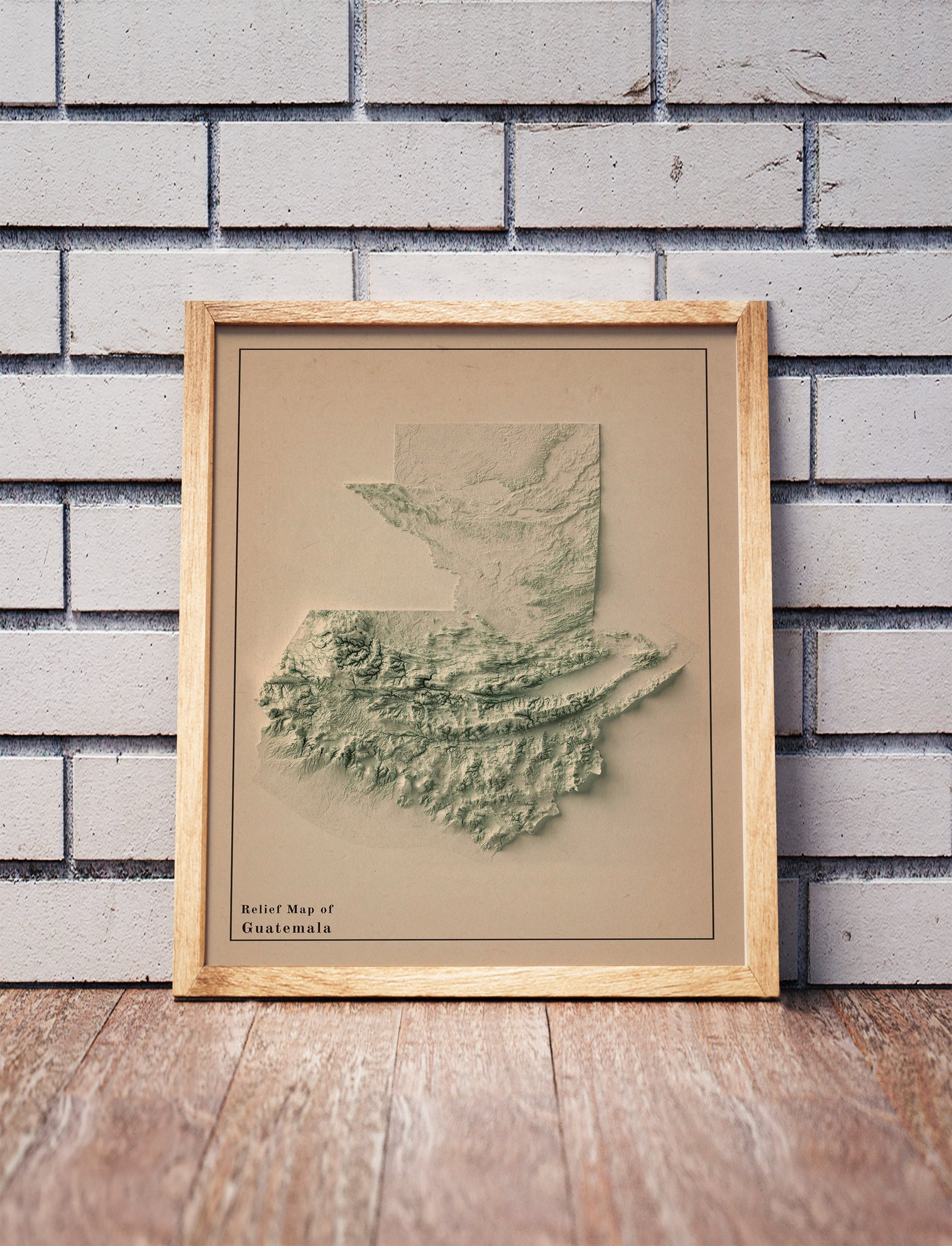 Vintage Guatemala shaded relief map in a wooden frame. Realistic terrain art print for home decor, displayed against a brick wall