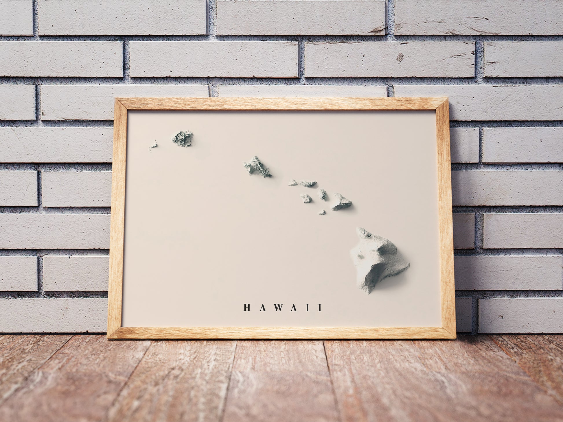 Hawaii shaded relief map in a wooden frame. Realistic terrain art print for home decor, displayed against a brick wall