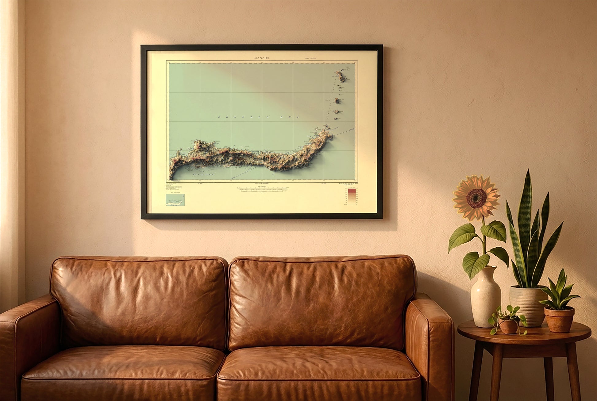 North Sulawesi, Celebes, Indonesia, vintage relief map in a black frame above a brown leather sofa. Boho living room with warm sunlight, sunflower, and indoor plants on a wooden side table