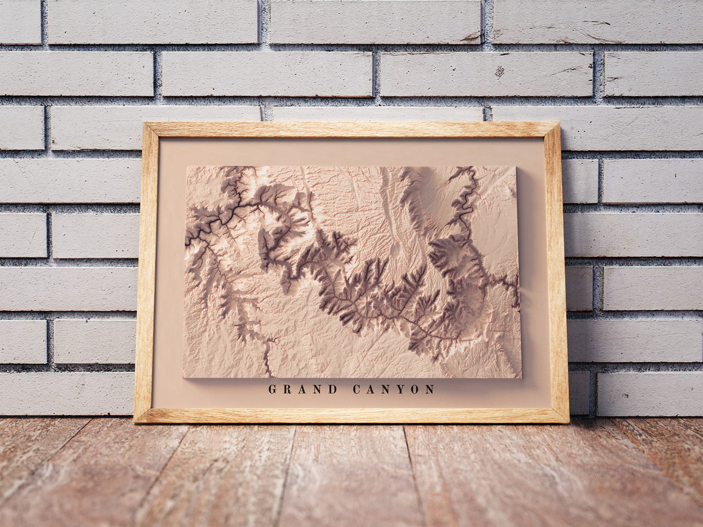 Grand Canyon shaded relief map in a wooden frame. Realistic terrain art print for home decor, displayed against a brick wall