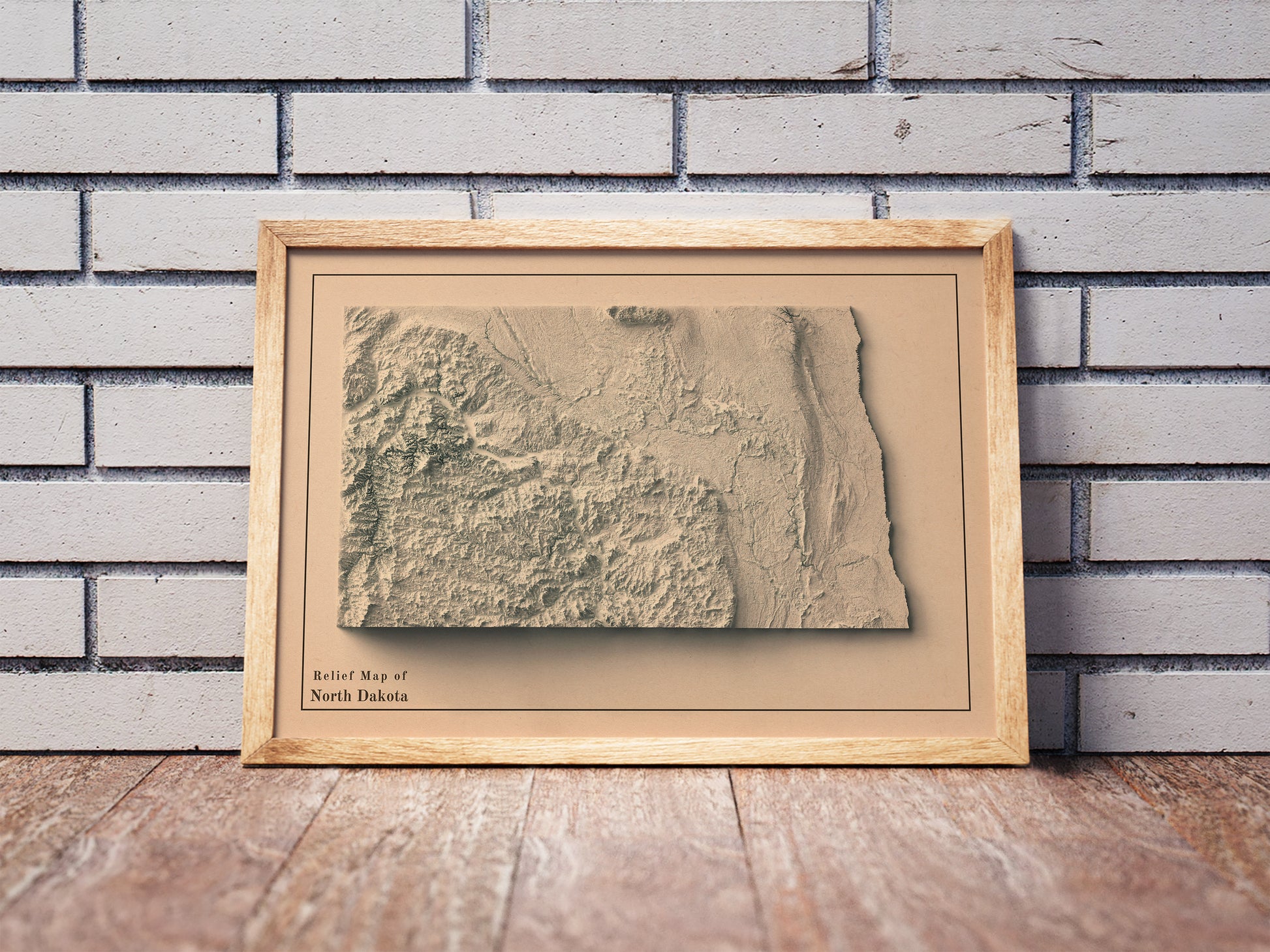 Vintage North Dakota shaded relief map in a wooden frame. Realistic terrain art print for home decor, displayed against a brick wall