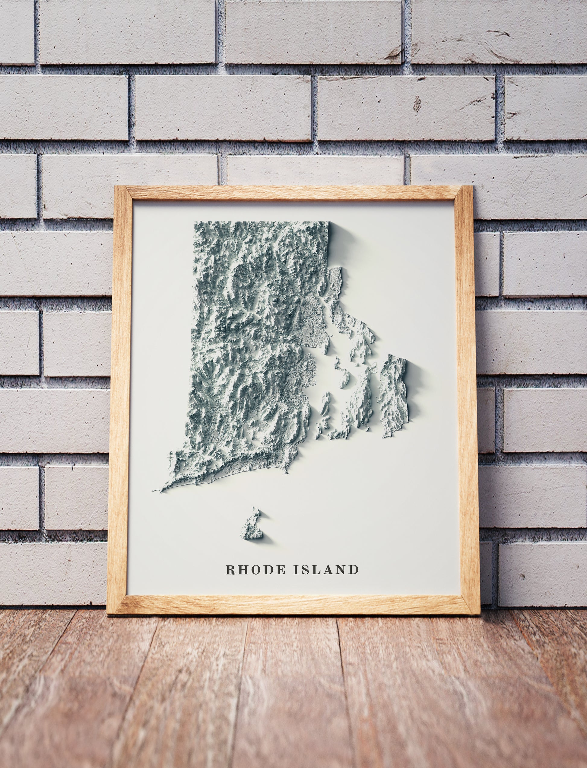 Rhode Island shaded relief map in a wooden frame. Realistic terrain art print for home decor, displayed against a brick wall